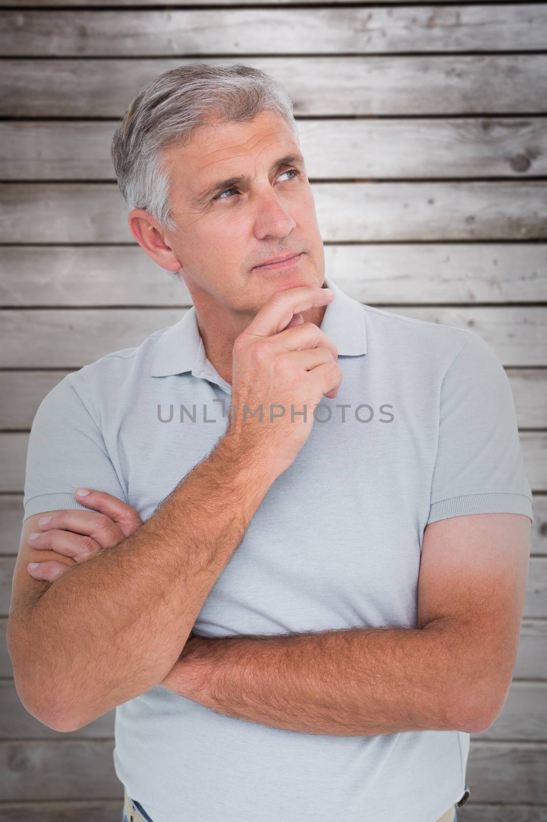 Casual man thinking with hand on chin against wooden planks