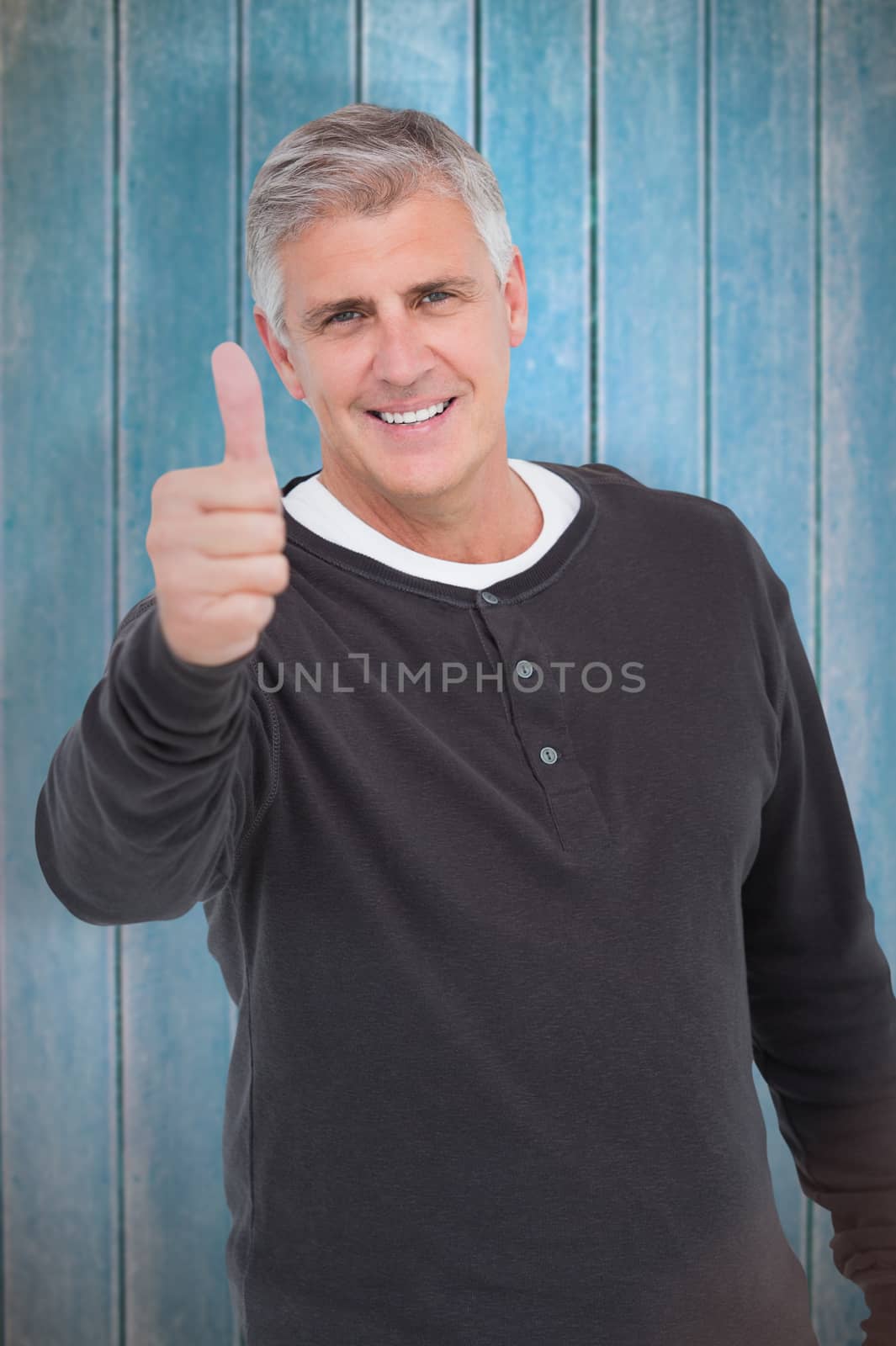 Casual man showing thubms up at camera against wooden planks