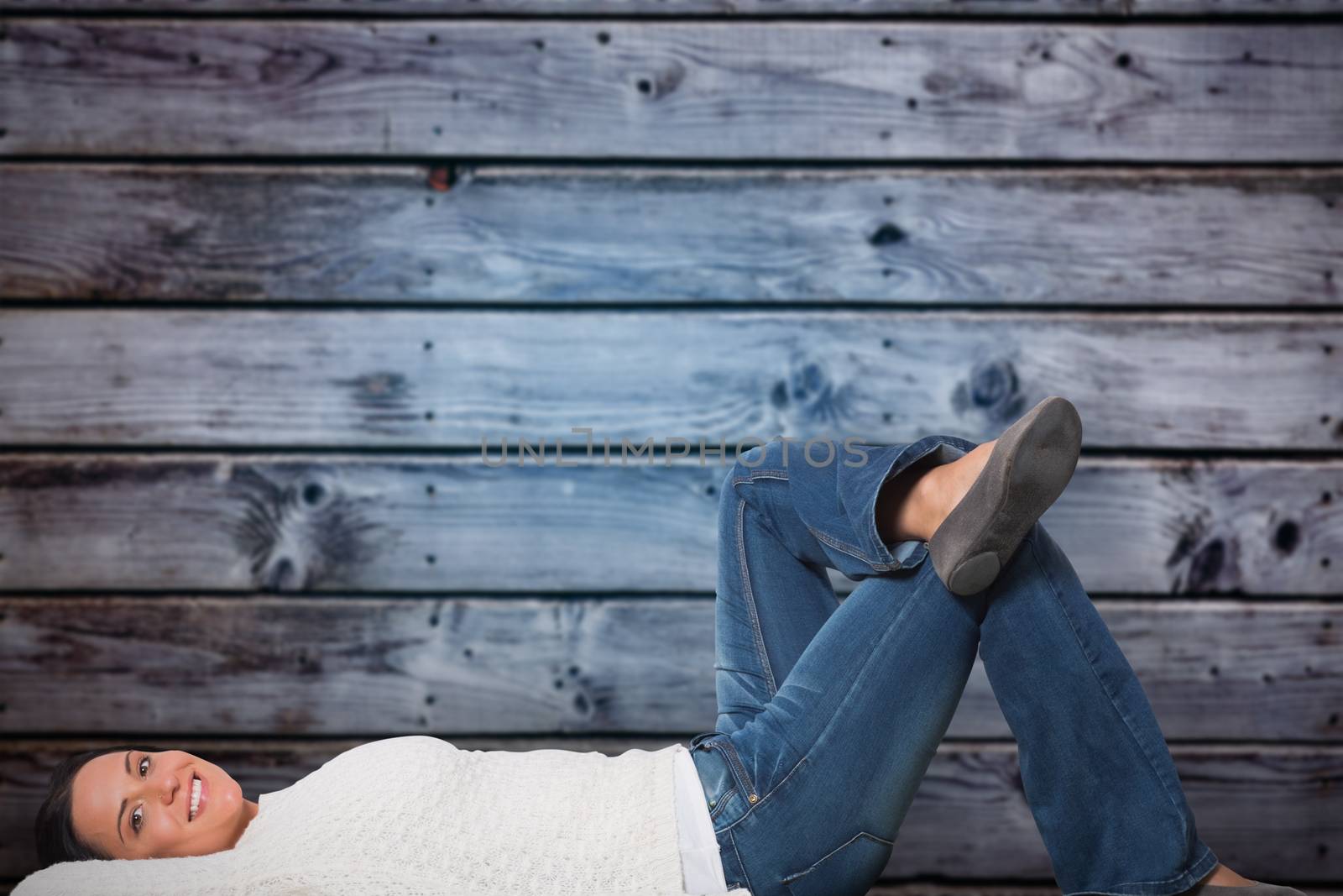 Young woman lying on floor smiling against grey wooden planks