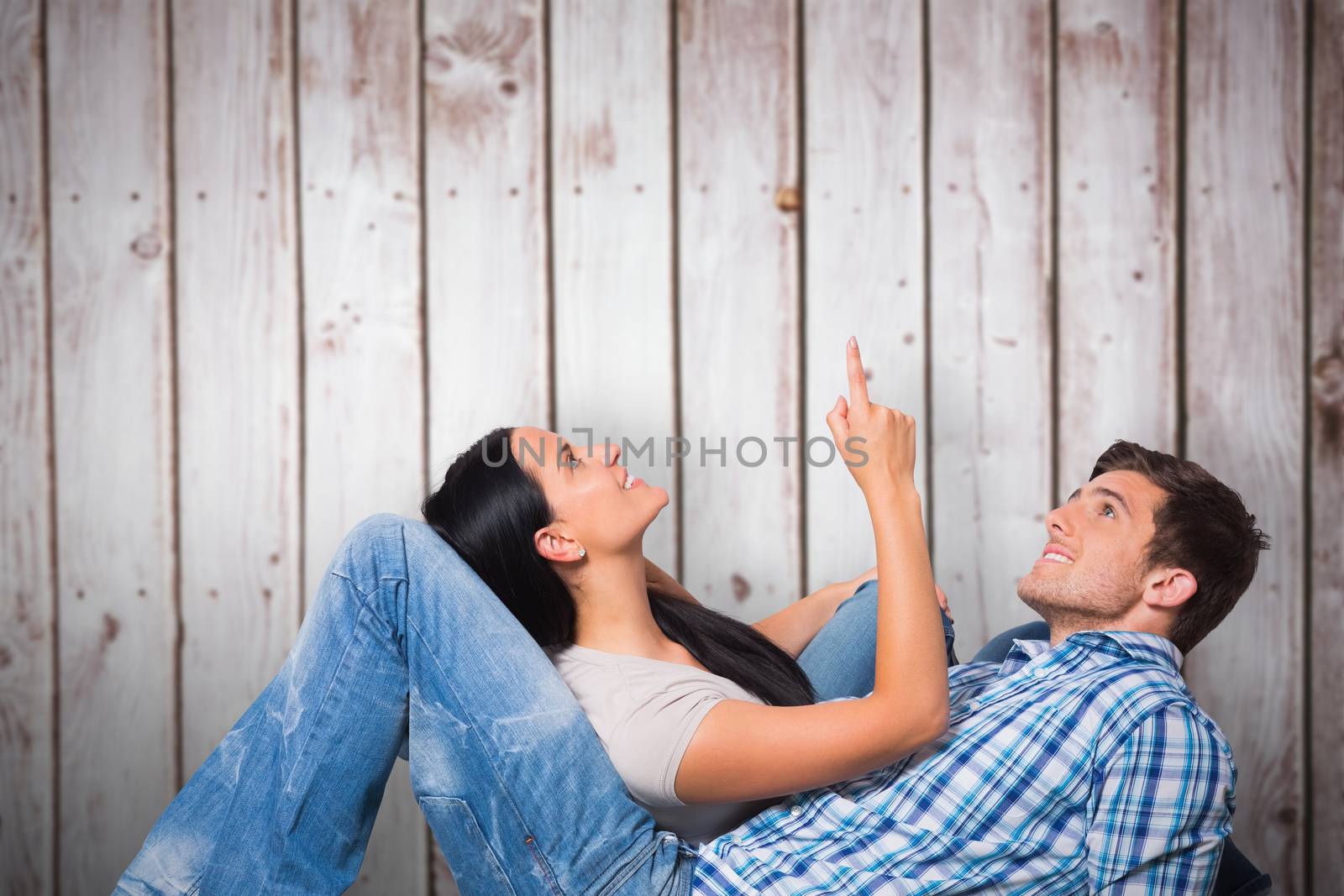 Young couple lying on floor smiling against wooden planks