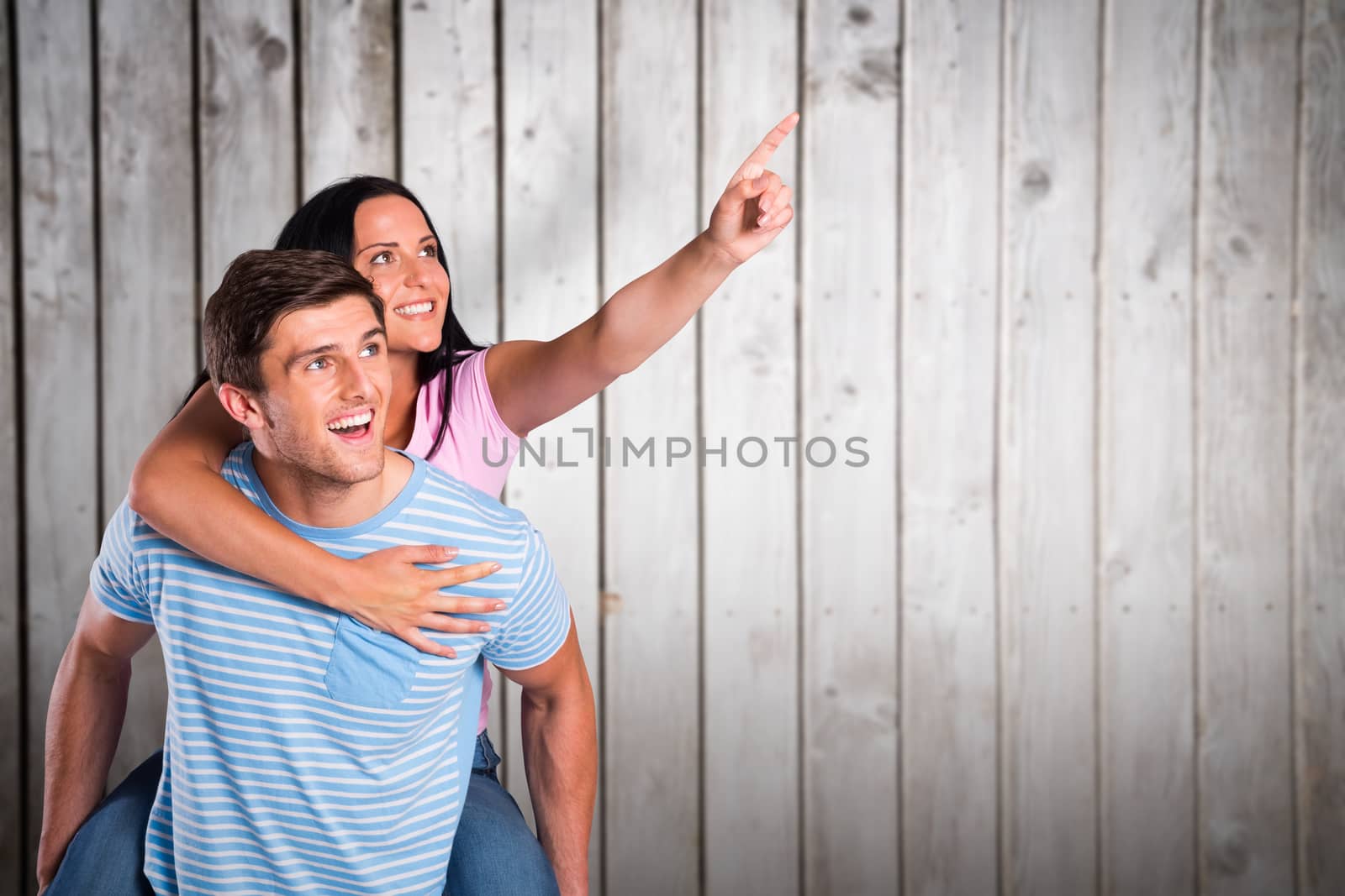 Young man giving girlfriend a piggyback ride against wooden planks