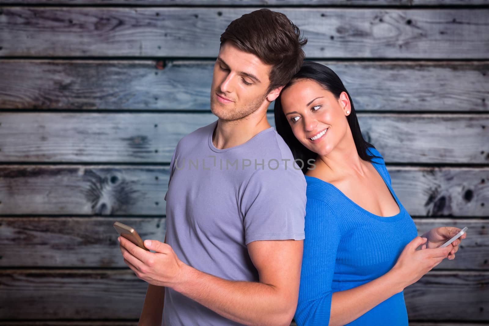 Young couple sending a text against grey wooden planks