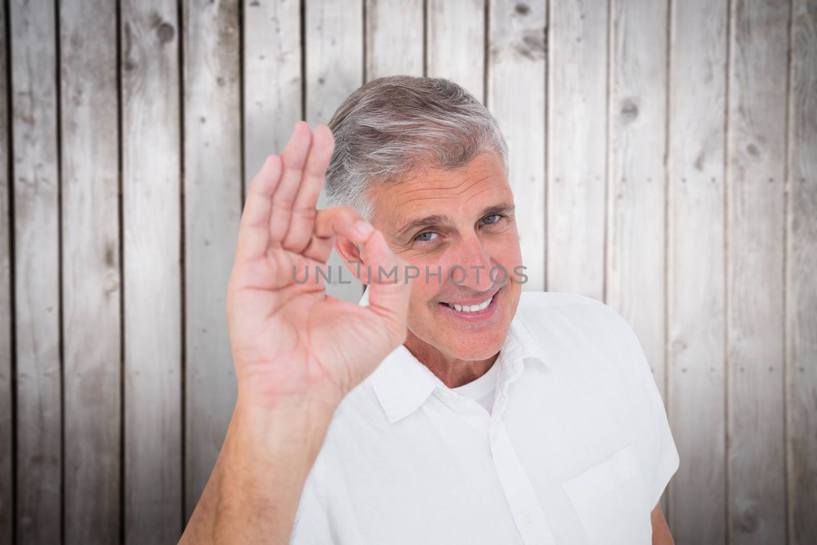 Casual man showing ok sign to camera against wooden planks