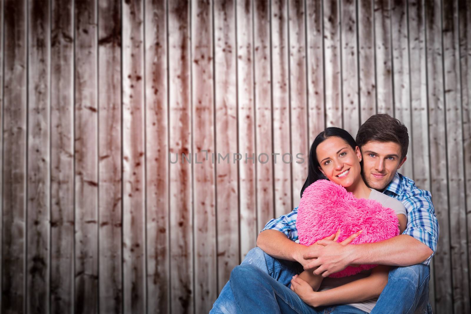 Young couple sitting on floor smiling against wooden planks