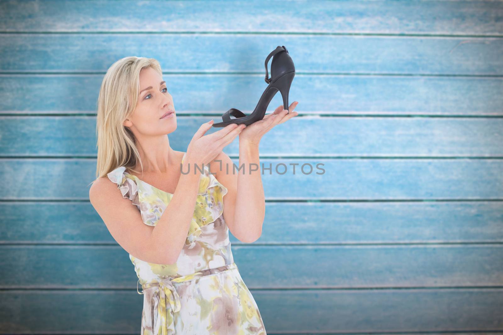 Elegant blonde admiring a shoe against wooden planks