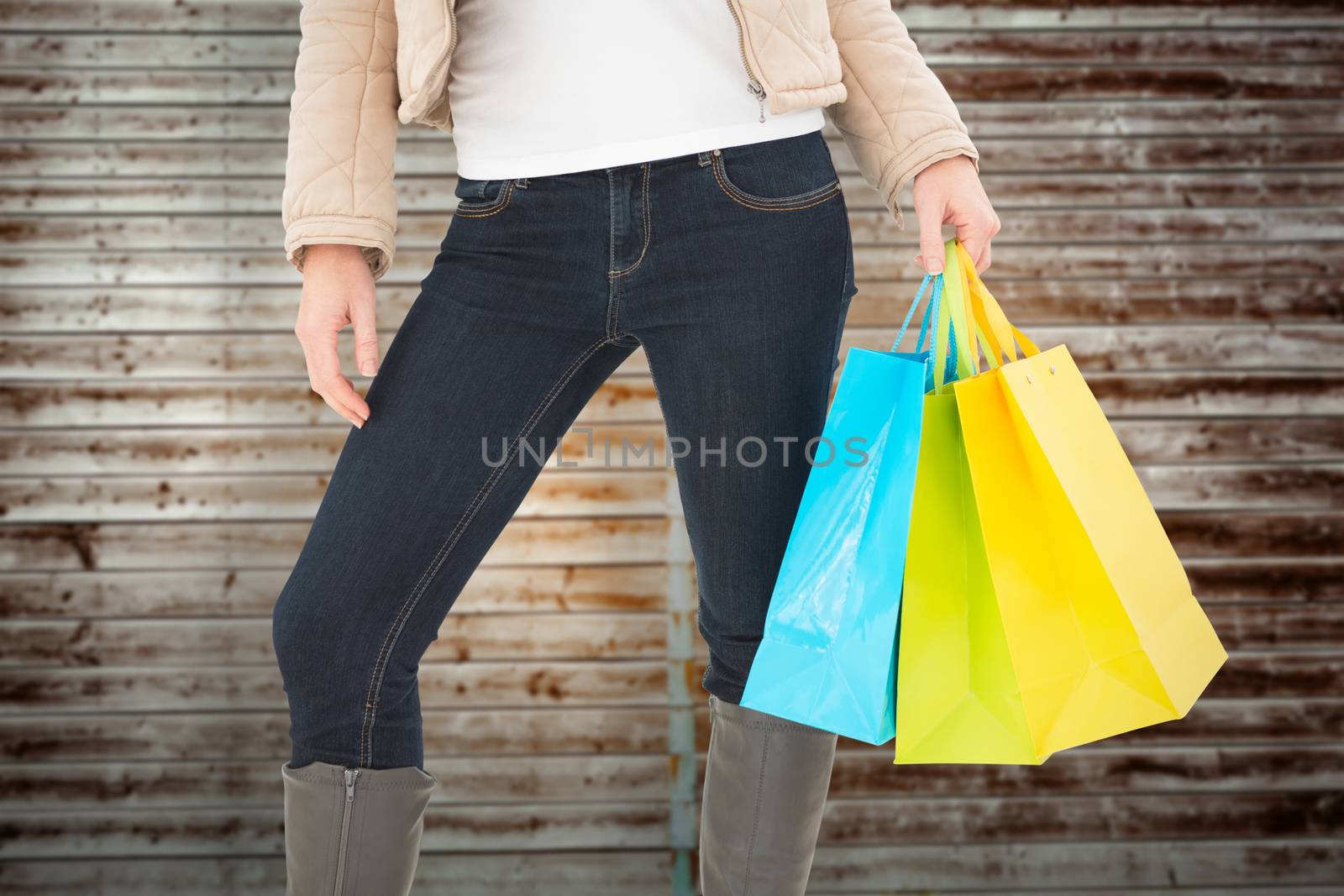 Mid section of woman holding shopping bags against wooden planks