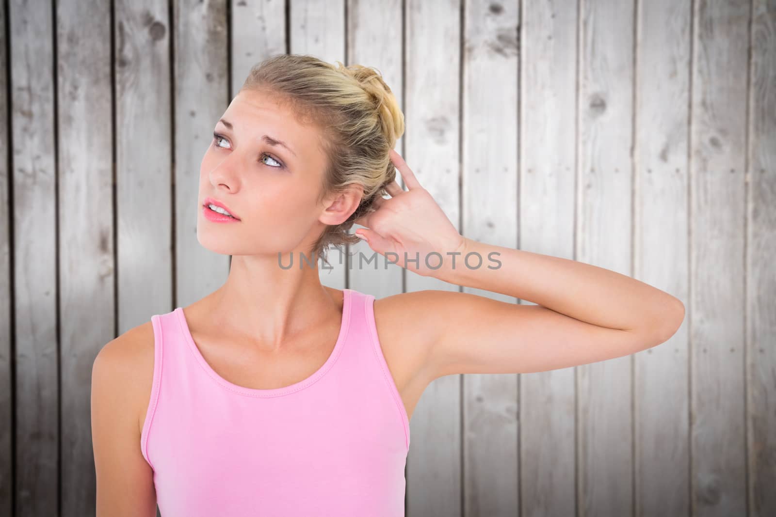 Pretty young blonde in pink looking up against wooden planks