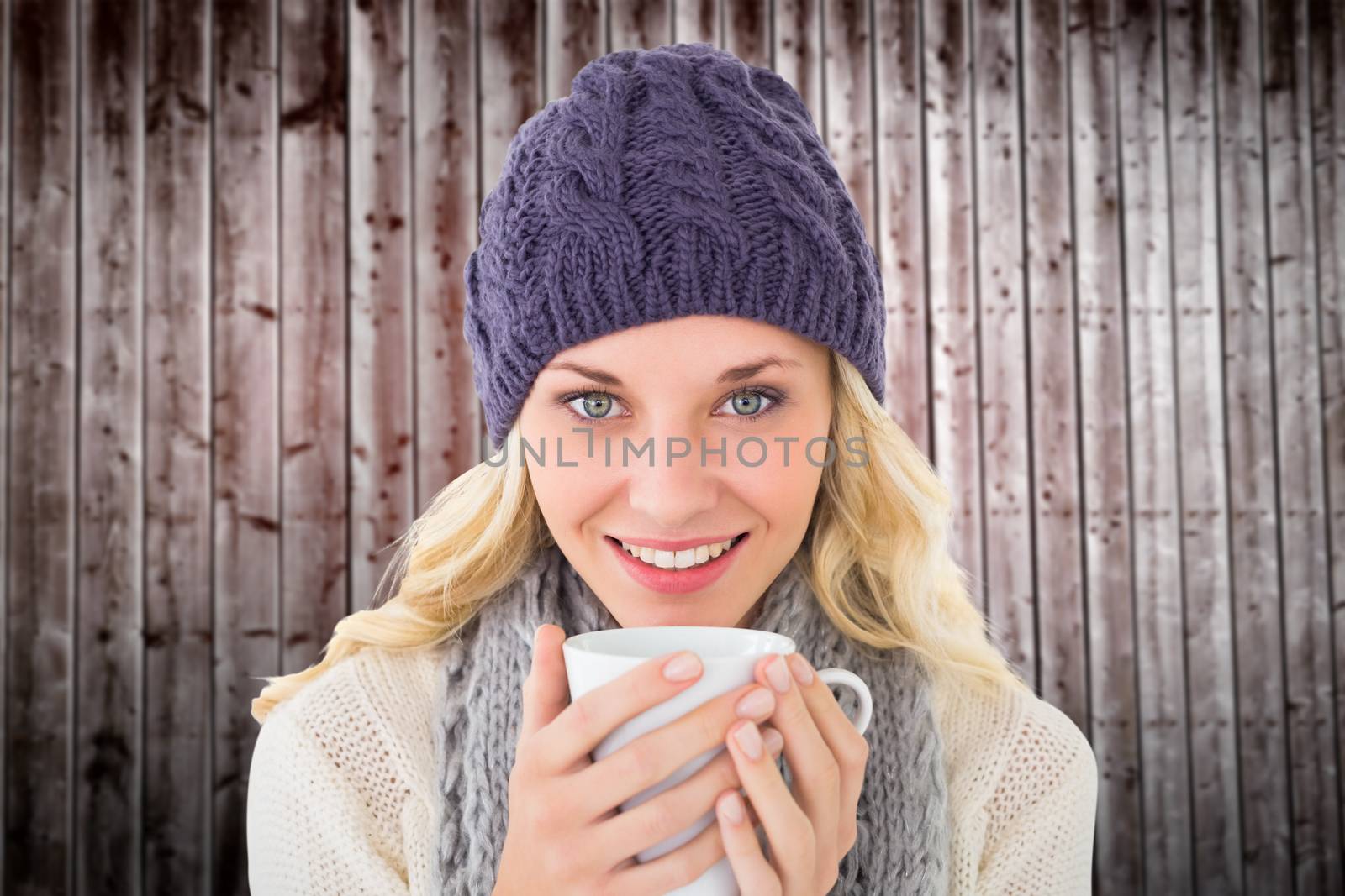 Pretty blonde in winter fashion holding mug against wooden planks