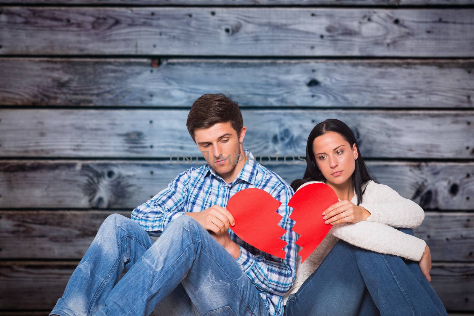 Composite image of young couple sitting on floor with broken heart by Wavebreakmedia