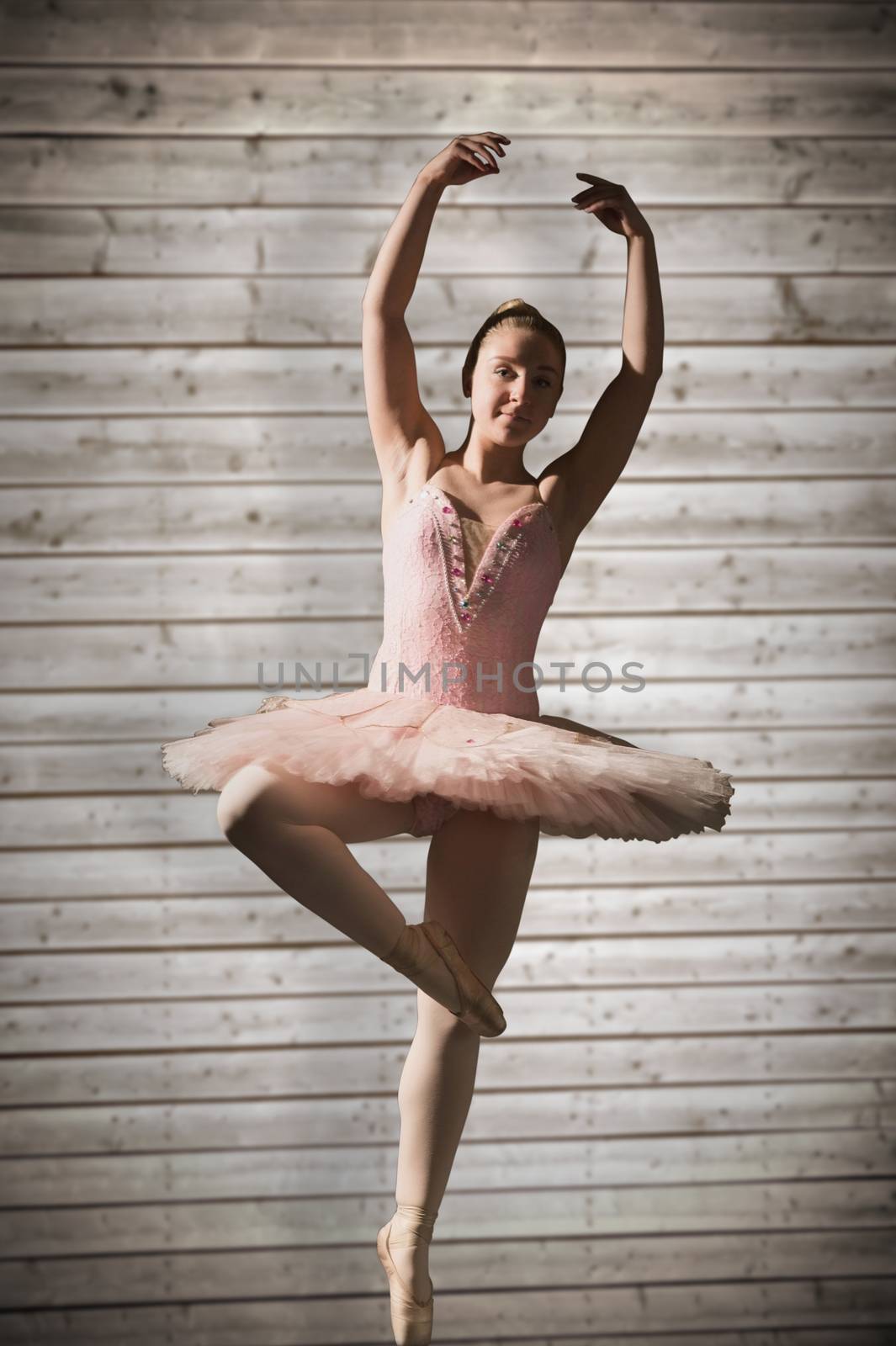 Pretty ballerina dancing against wooden planks background
