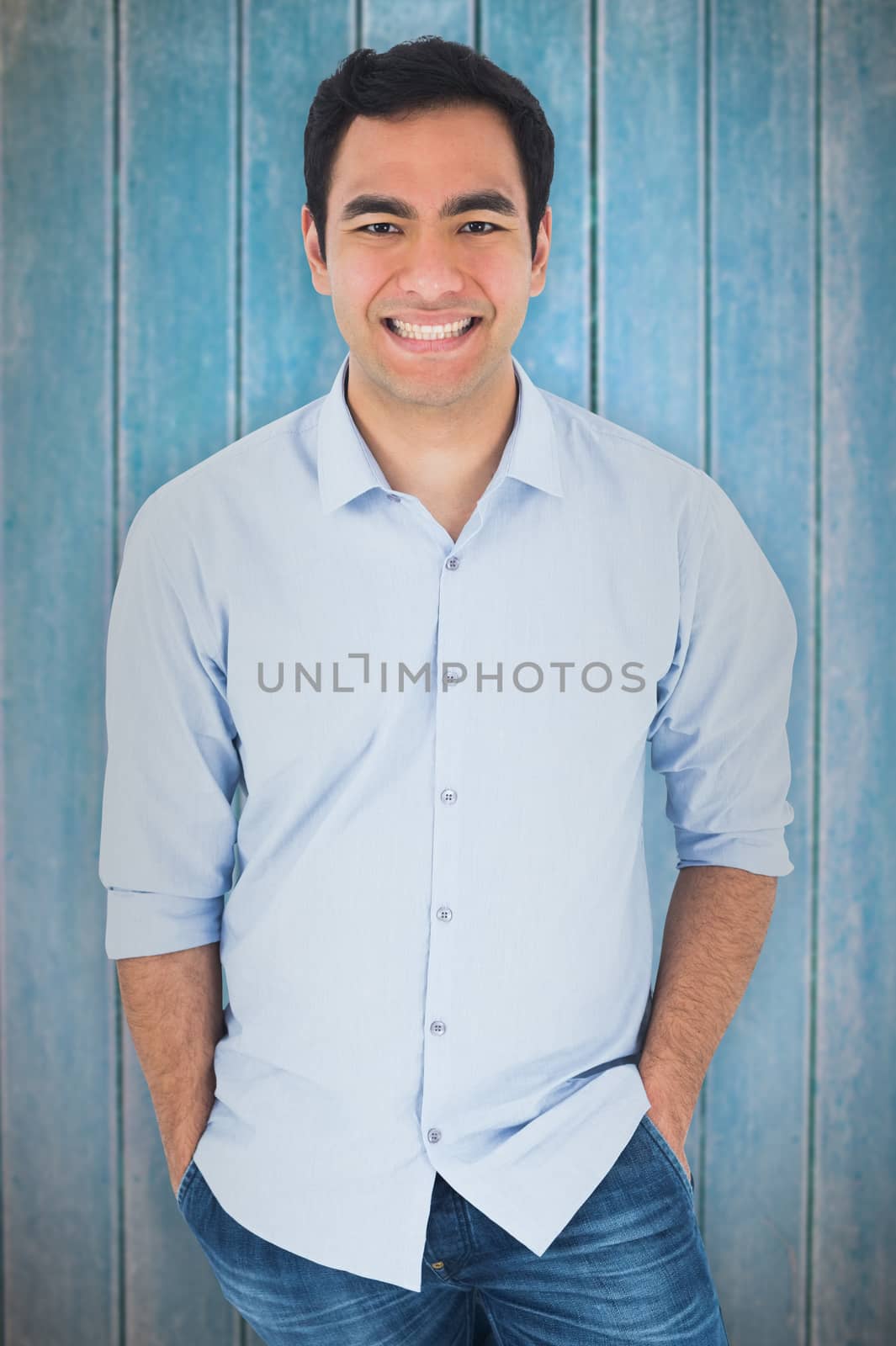 Smiling casual man standing against wooden planks