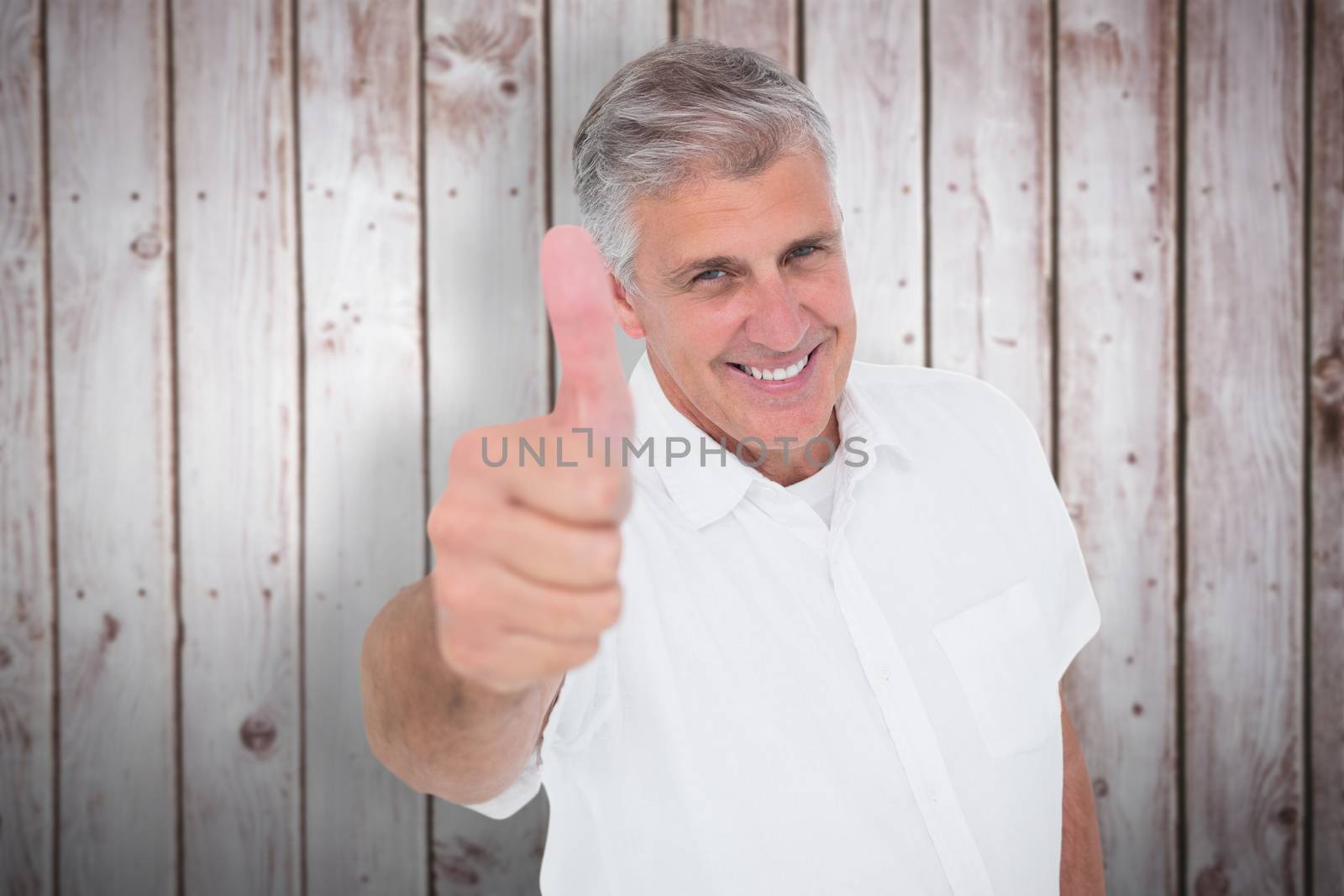 Casual man showing thumbs up at camera against wooden planks