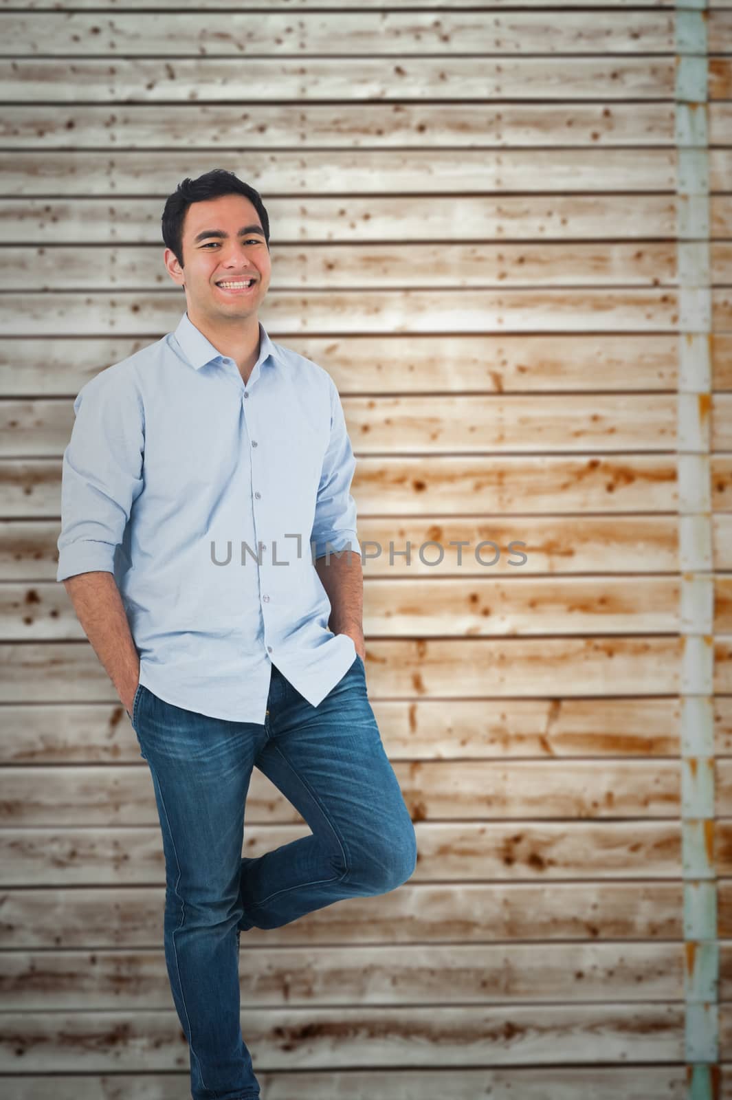Smiling casual man standing against faded pine wooden planks