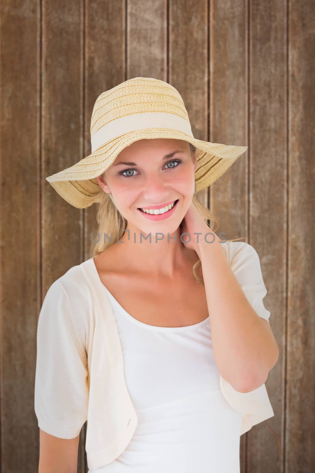 Attractive young blonde smiling at camera in sunhat against wooden planks background