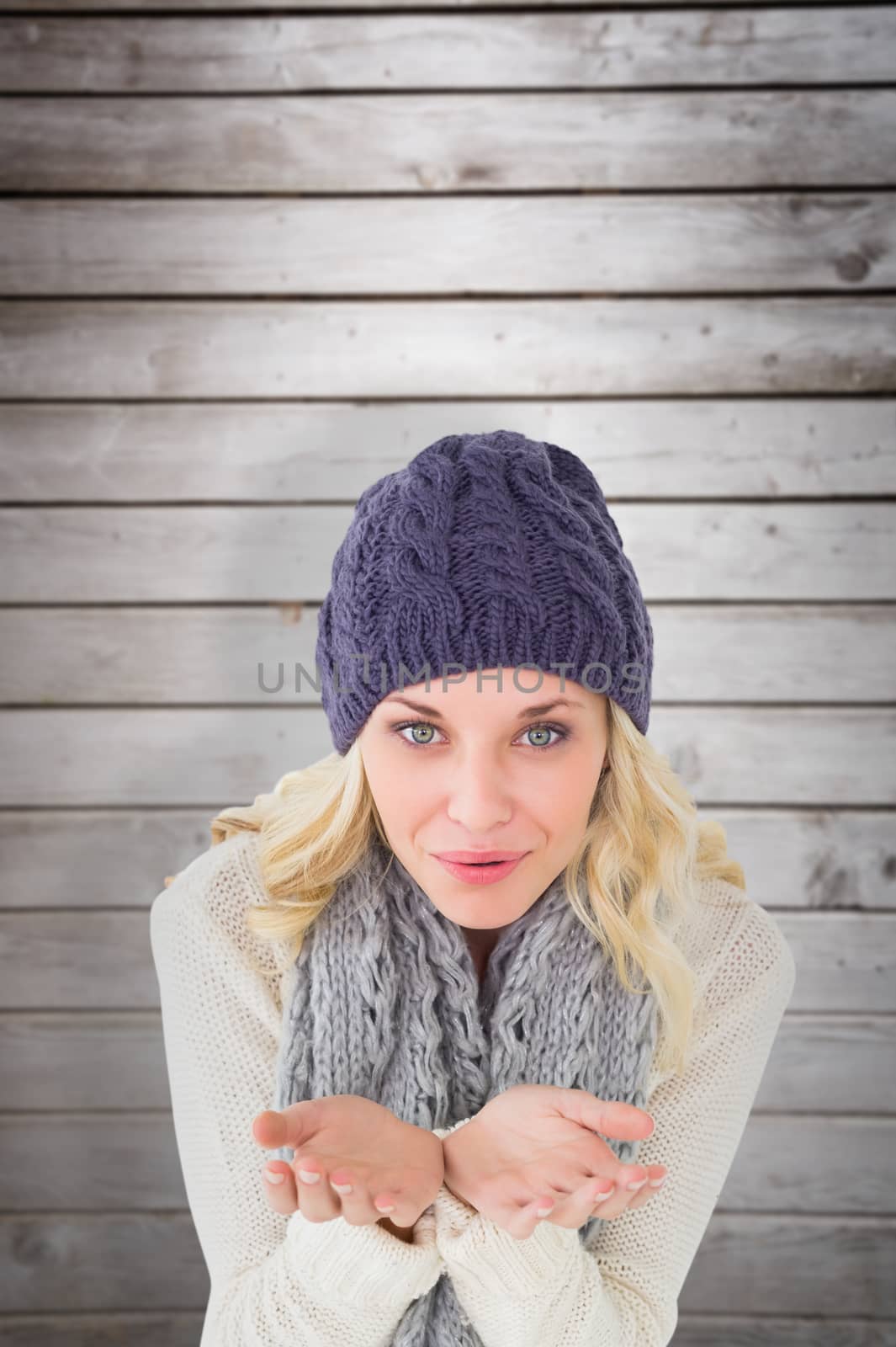 Composite image of pretty blonde in winter fashion blowing over hands by Wavebreakmedia