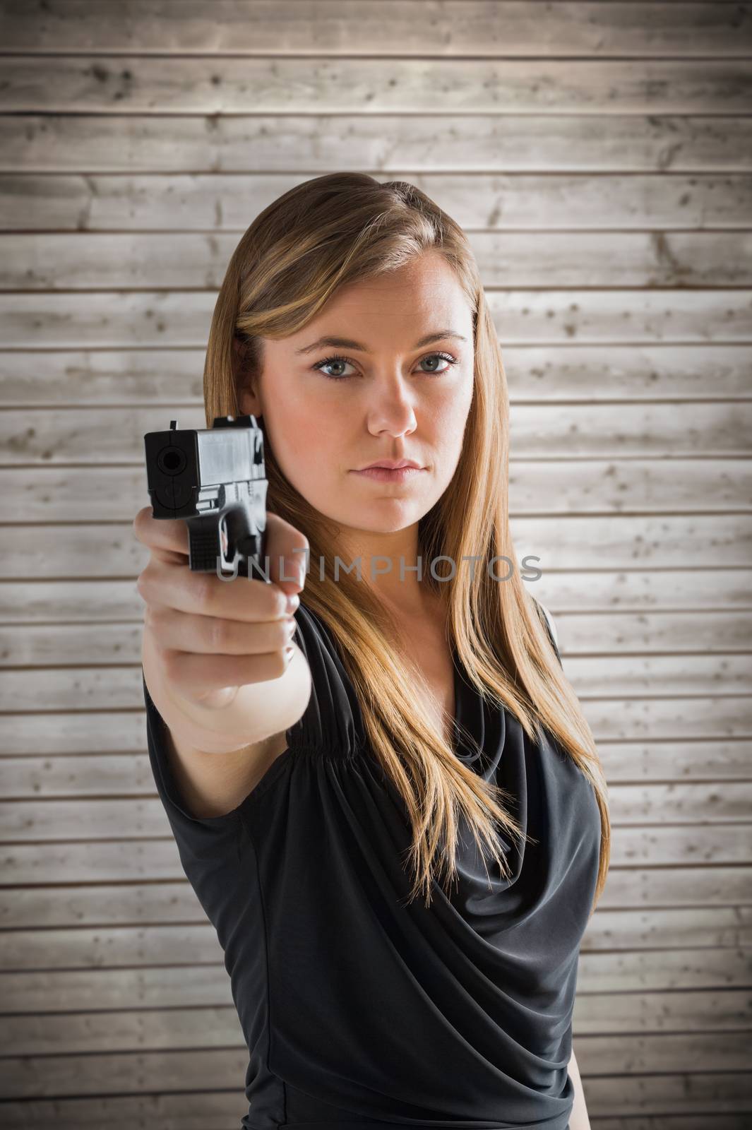Femme fatale pointing gun at camera against wooden planks background