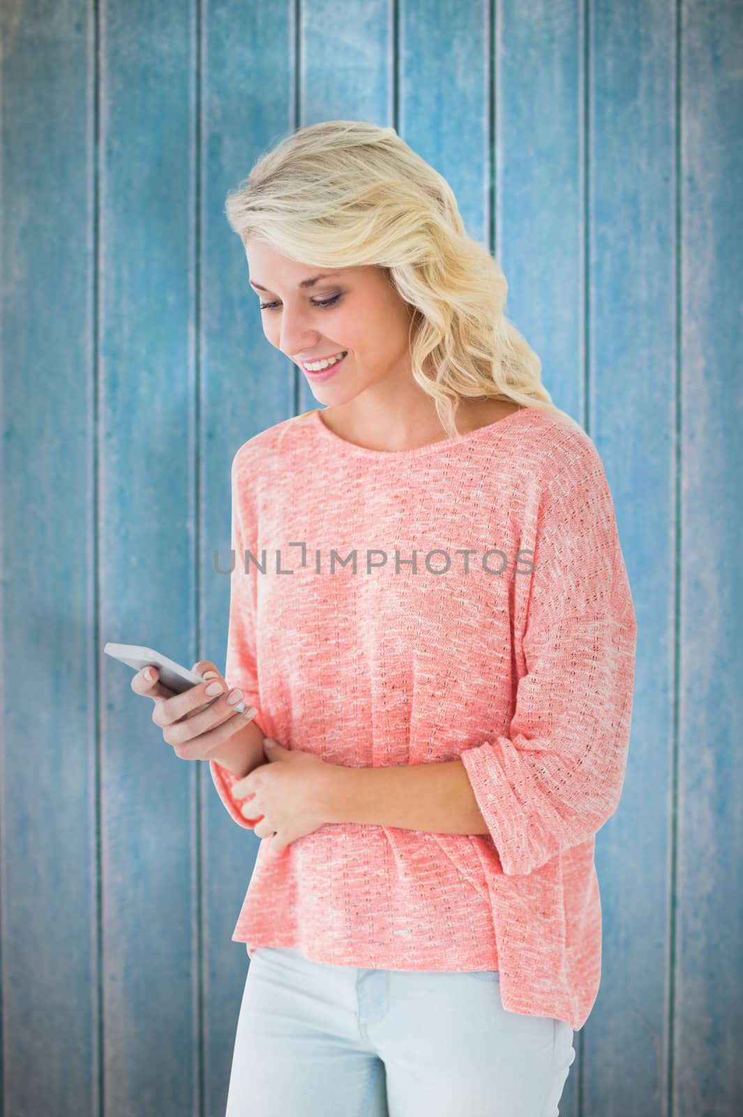 Pretty blonde using her smartphone against wooden planks