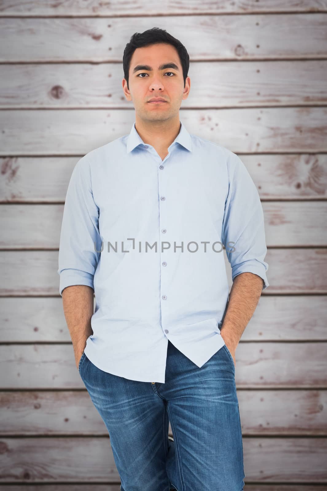 Unsmiling casual man standing against wooden planks