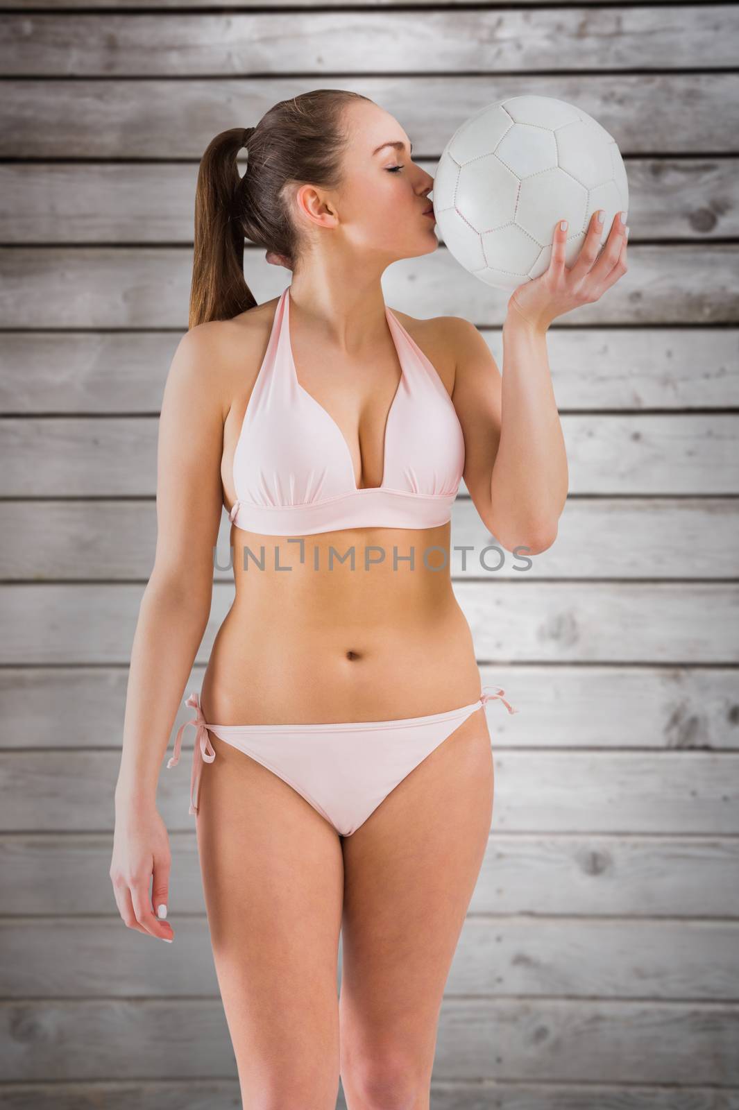 Composite image of pretty girl in bikini holding football by Wavebreakmedia