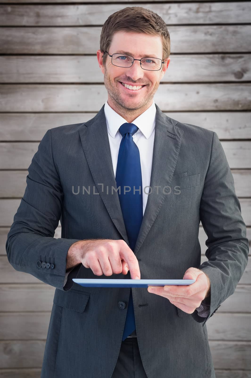 Businessman using his tablet pc  against wooden planks