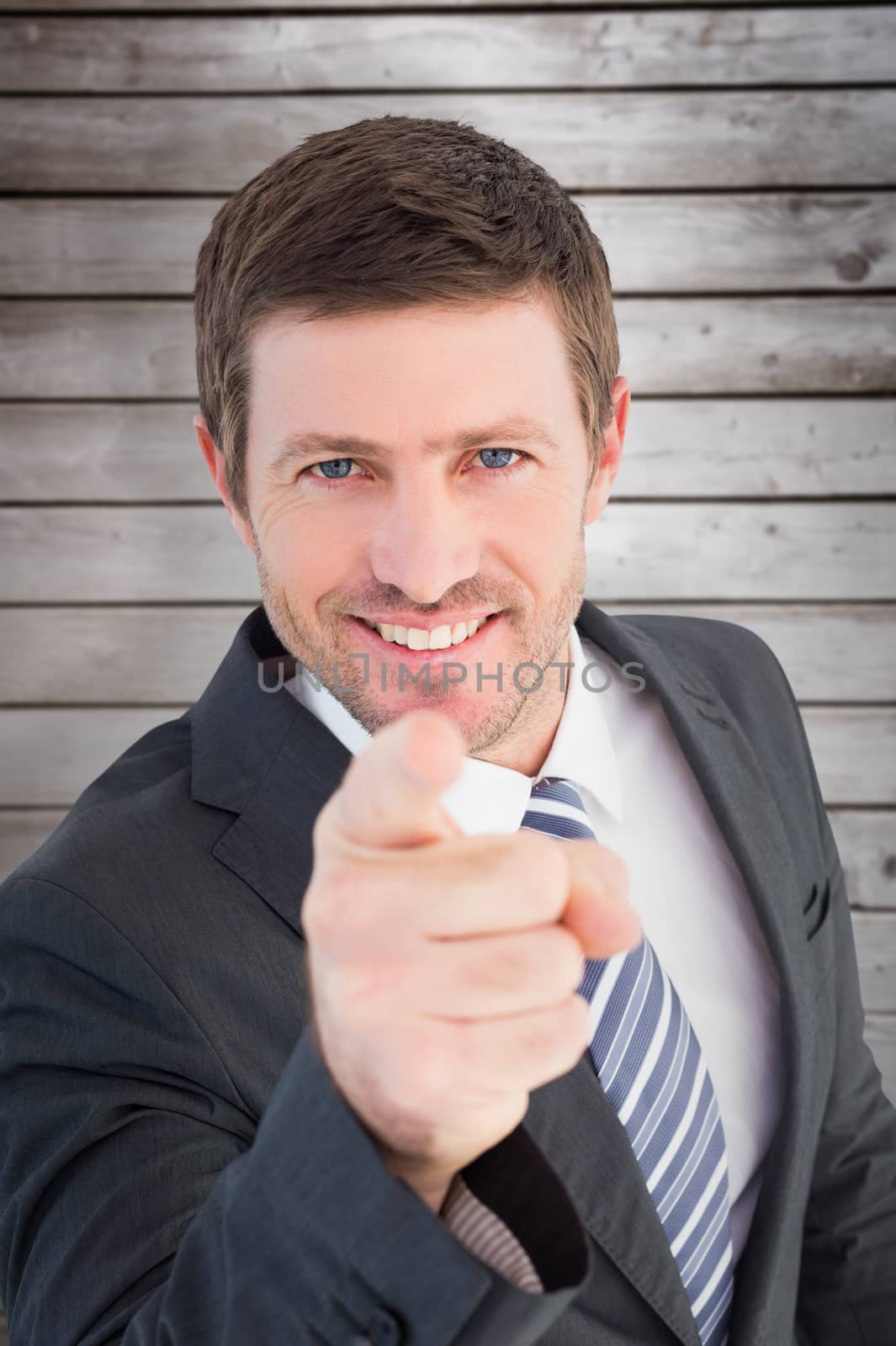 Businessman smiling and pointing against wooden planks