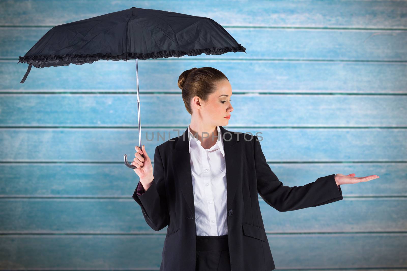 Businesswoman holding a black umbrella against wooden planks