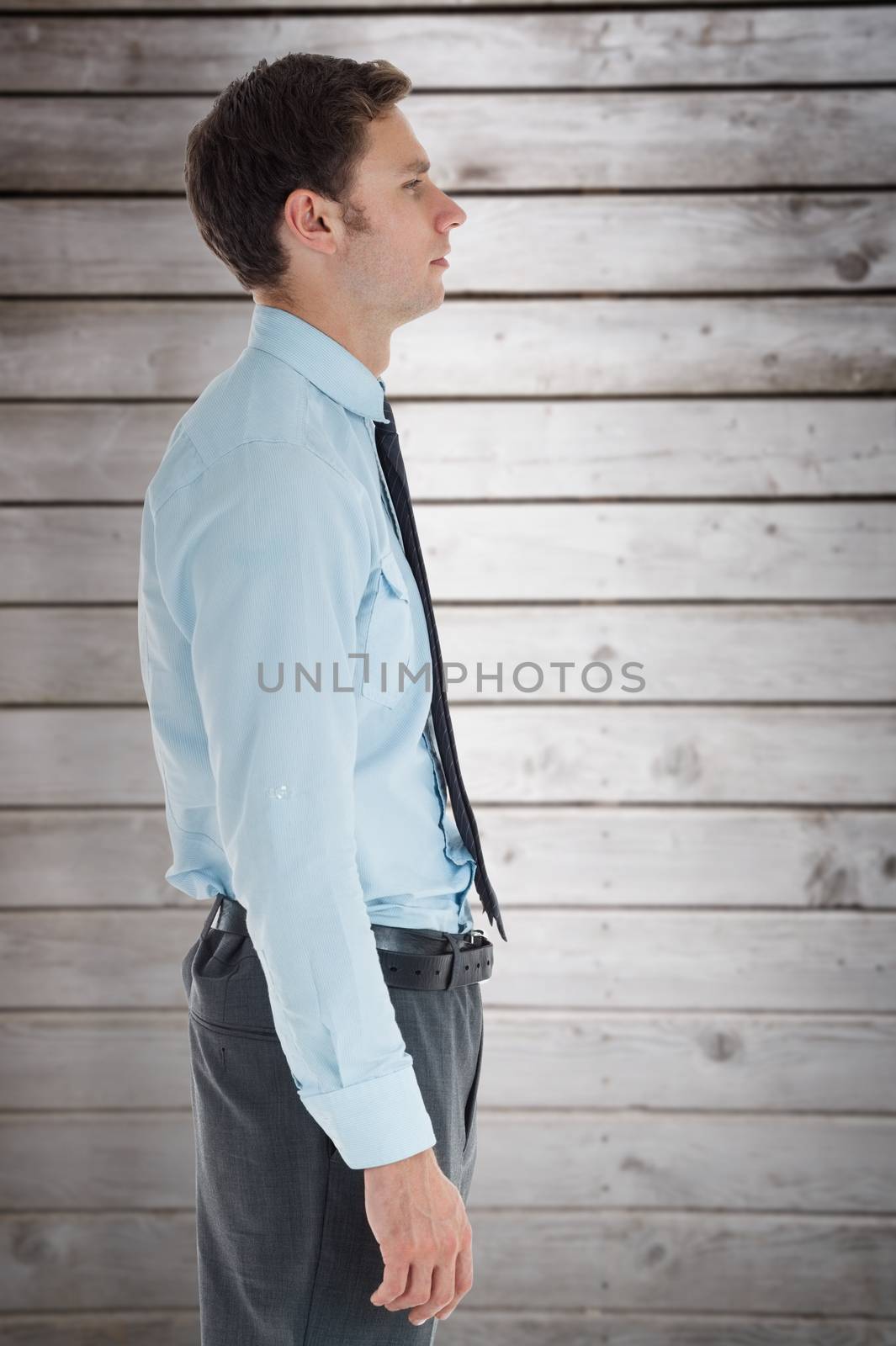 Serious businessman standing with hand in pocket against wooden planks
