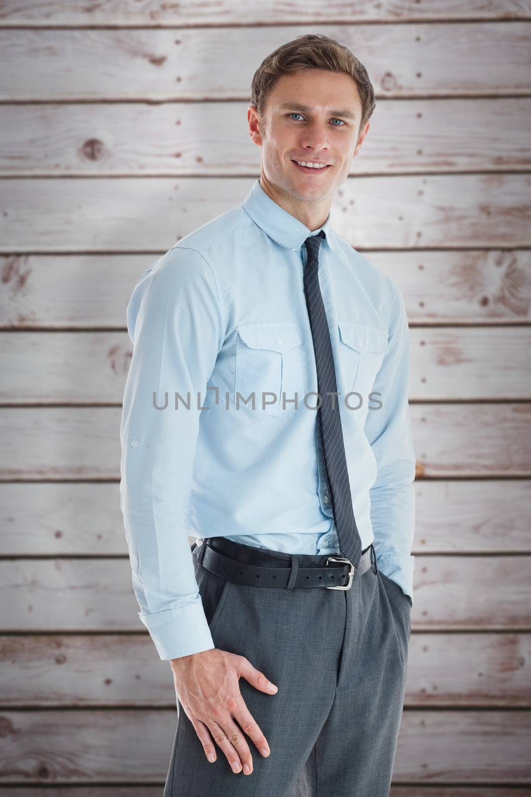 Smiling businessman standing with hand in pocket against wooden planks