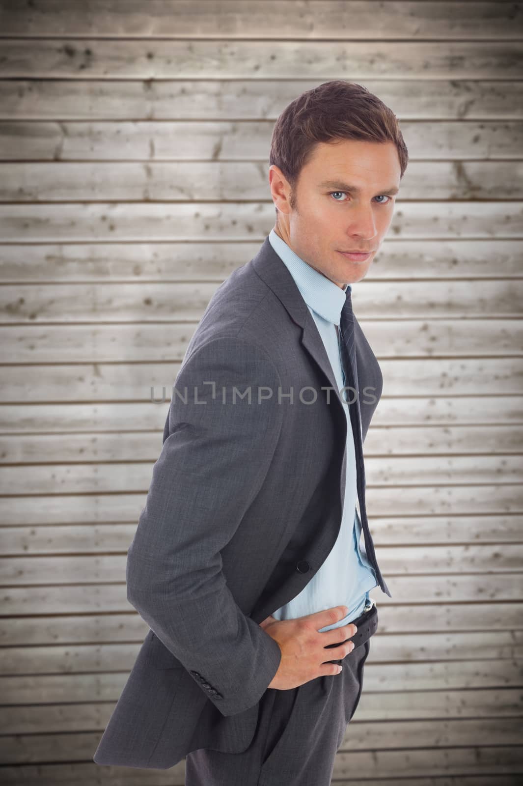 Composite image of serious businessman standing with hands on hips by Wavebreakmedia