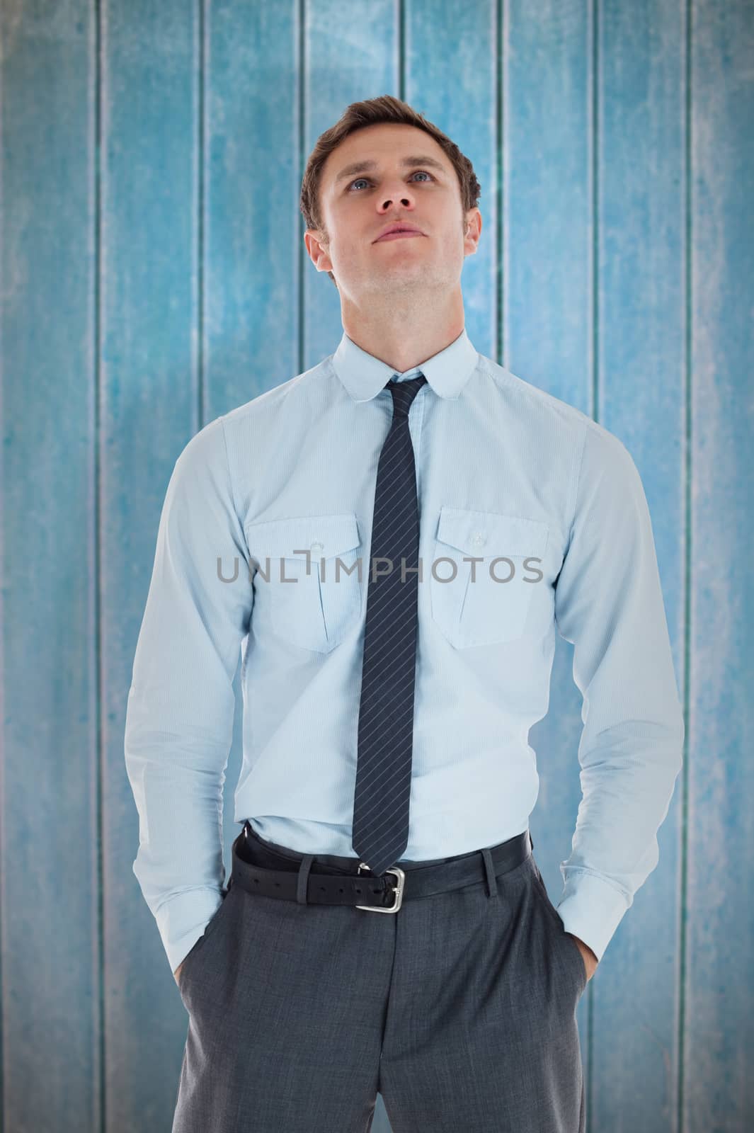 Serious businessman standing with hands in pockets against wooden planks