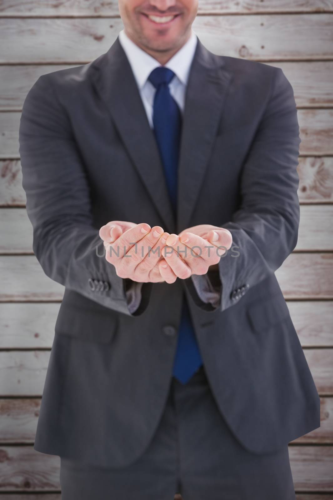 Smiling businessman presenting with hands against wooden planks