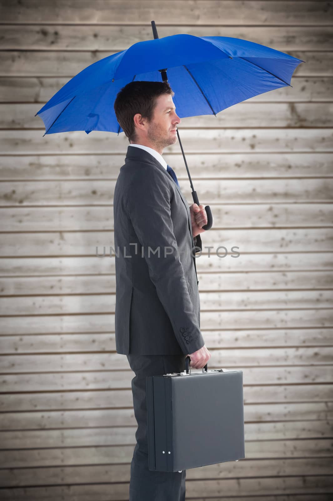 Composite image of serious businessman holding his umbrella and briefcase by Wavebreakmedia