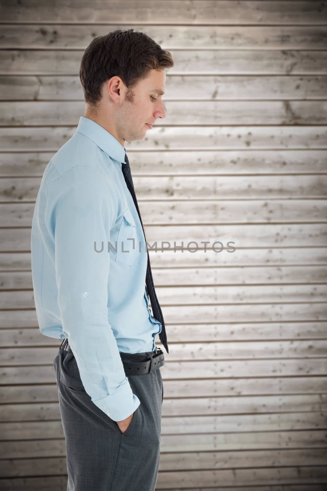 Serious businessman standing with hand in pocket against wooden planks background