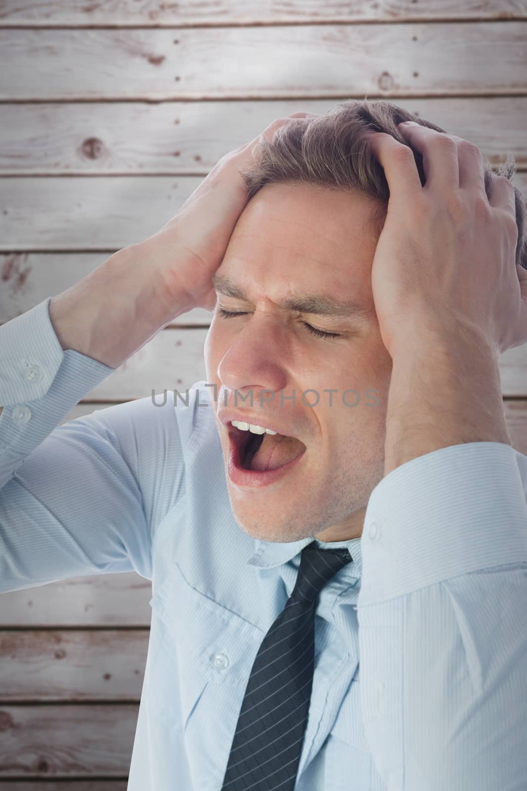 Stressed businessman with hands on head against wooden planks