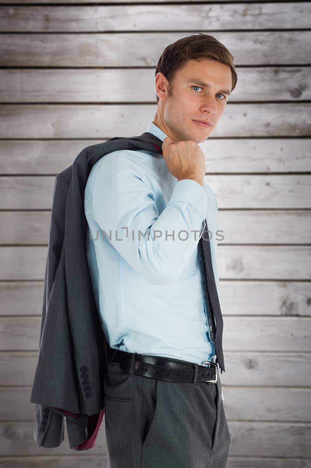 Serious businessman holding his jacket against wooden planks