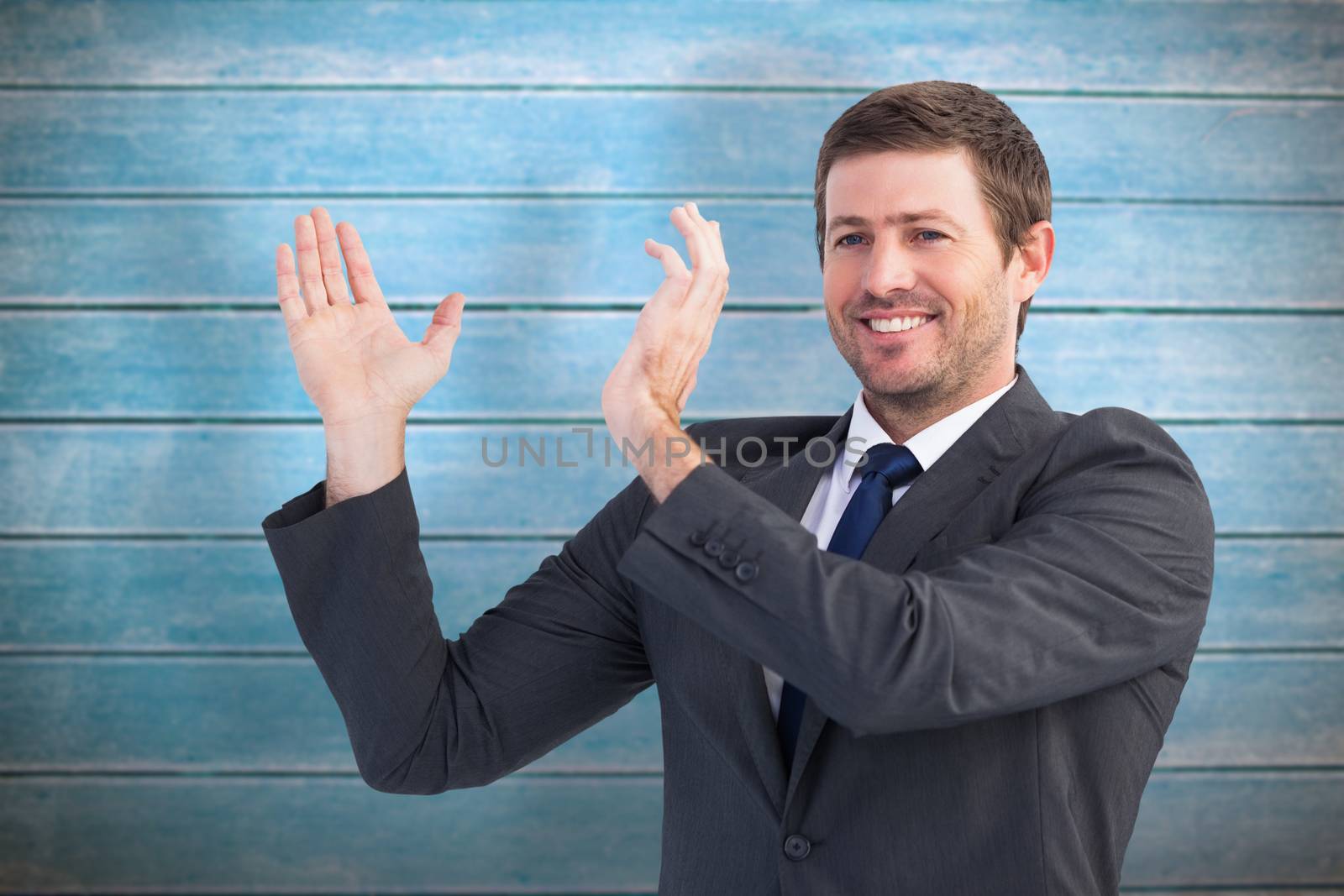 Smiling businessman showing something with his hands against wooden planks