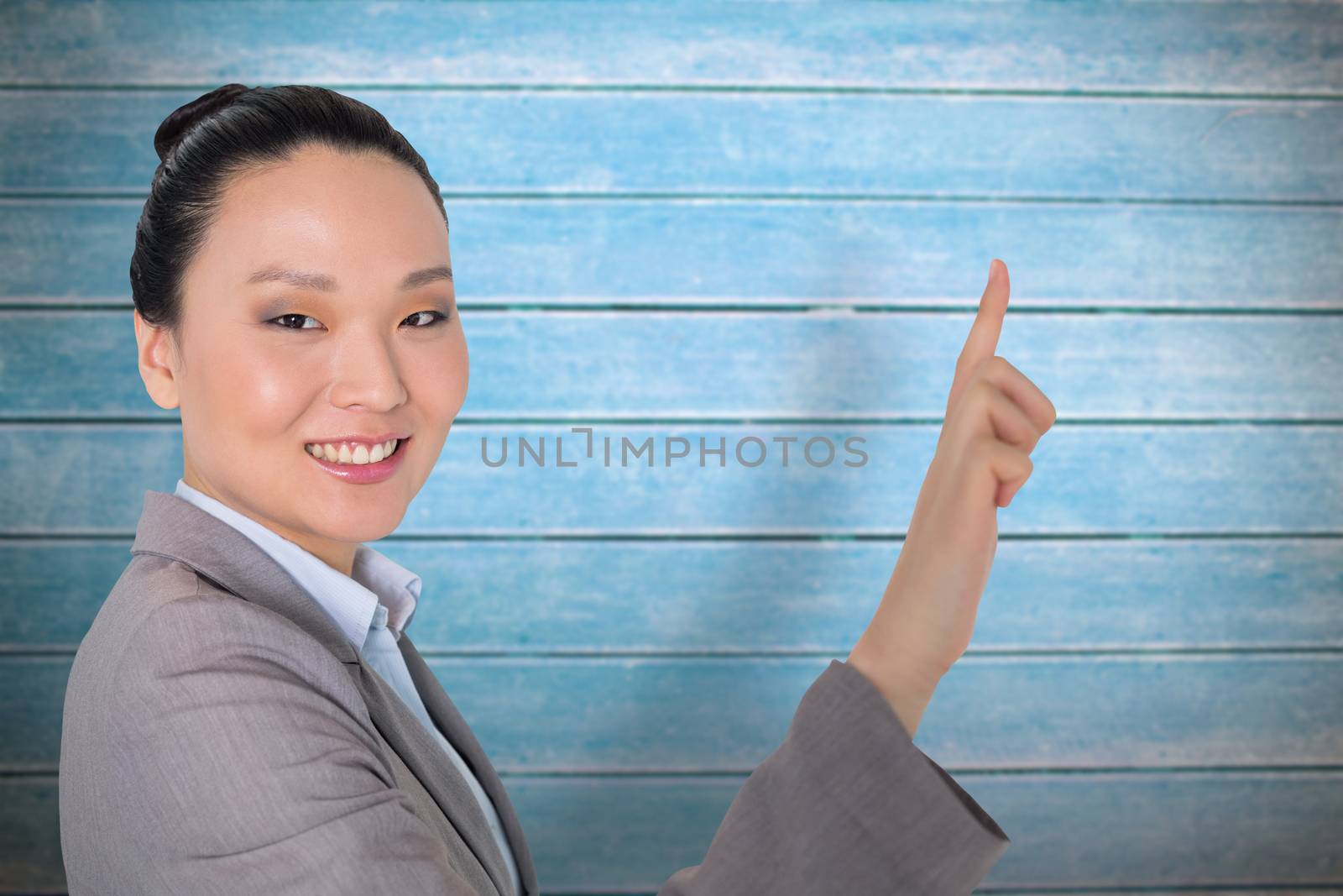 Smiling asian businesswoman pointing against wooden planks