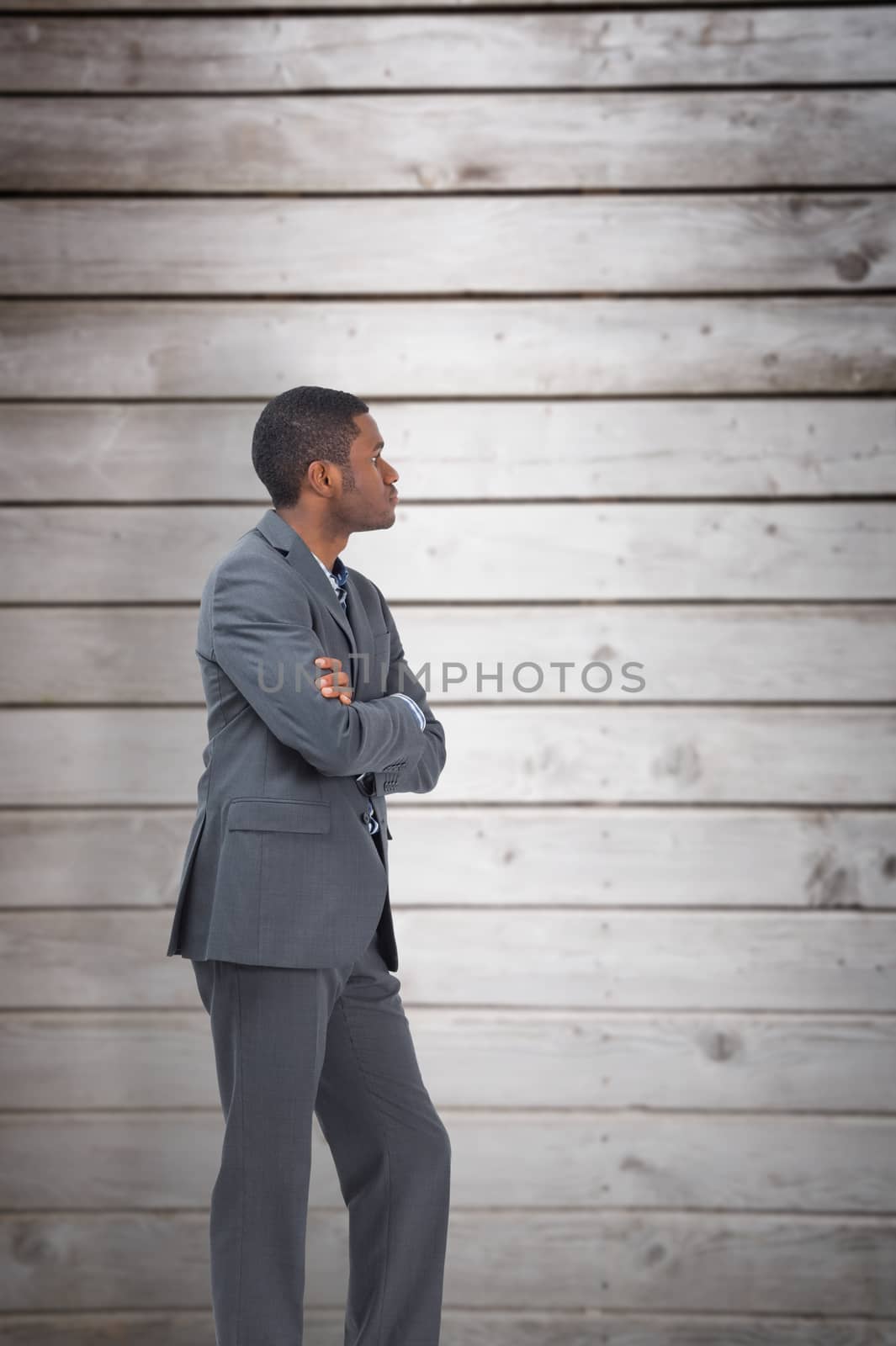 Businessman standing with arms crossed against wooden planks