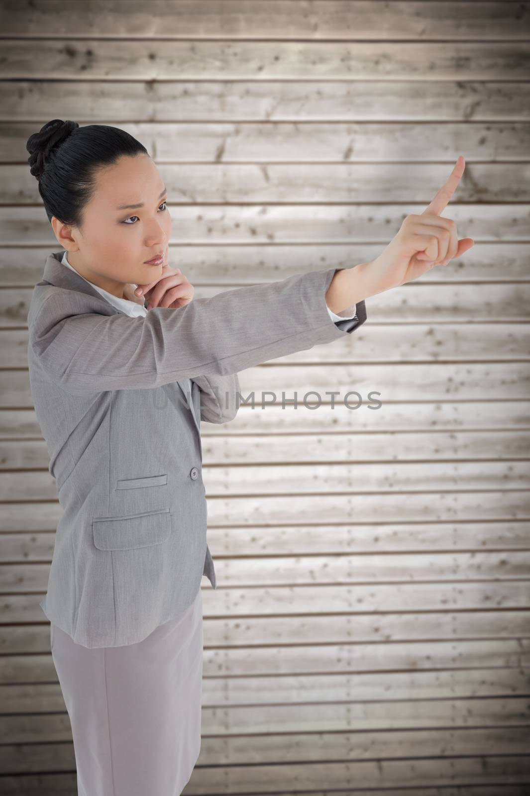 Unsmiling thinking asian businesswoman pointing against wooden planks background