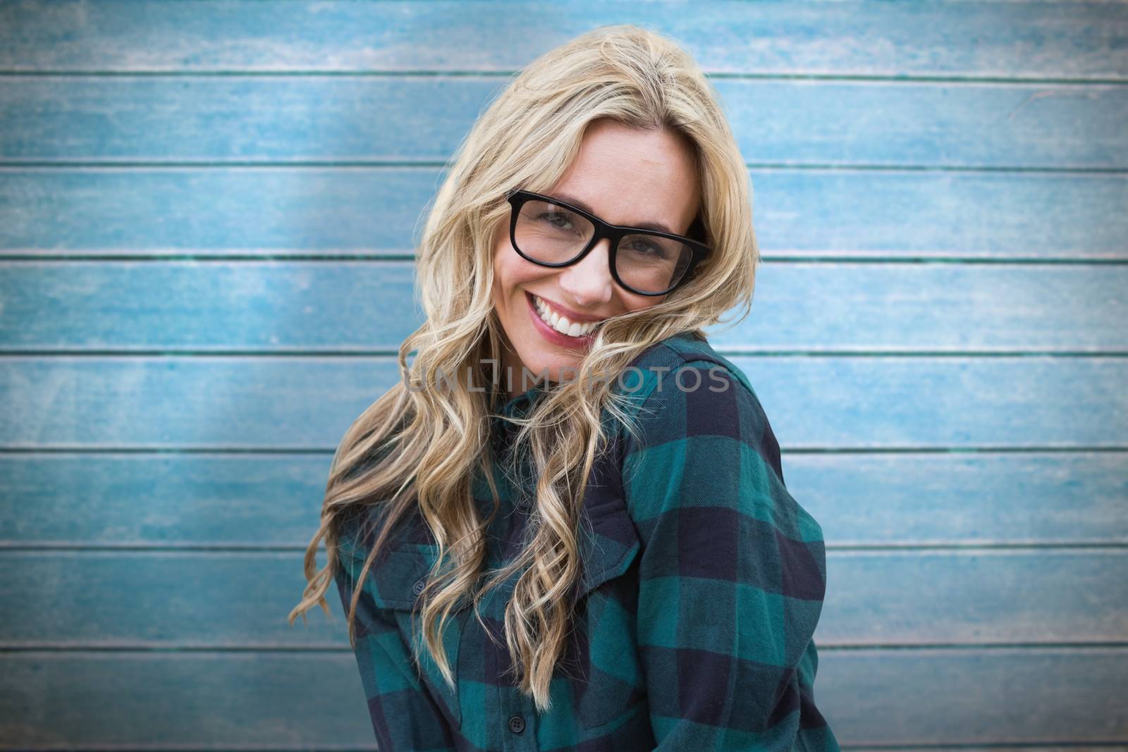 Pretty blonde smiling at camera against wooden planks