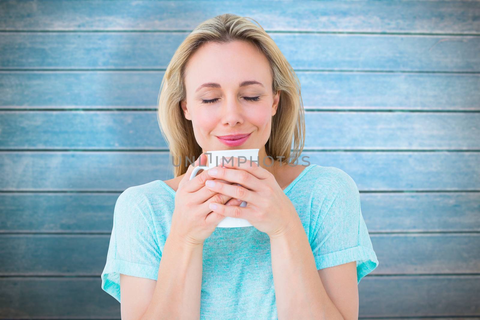 Cheerful blonde holding mug of hot drinking against wooden planks