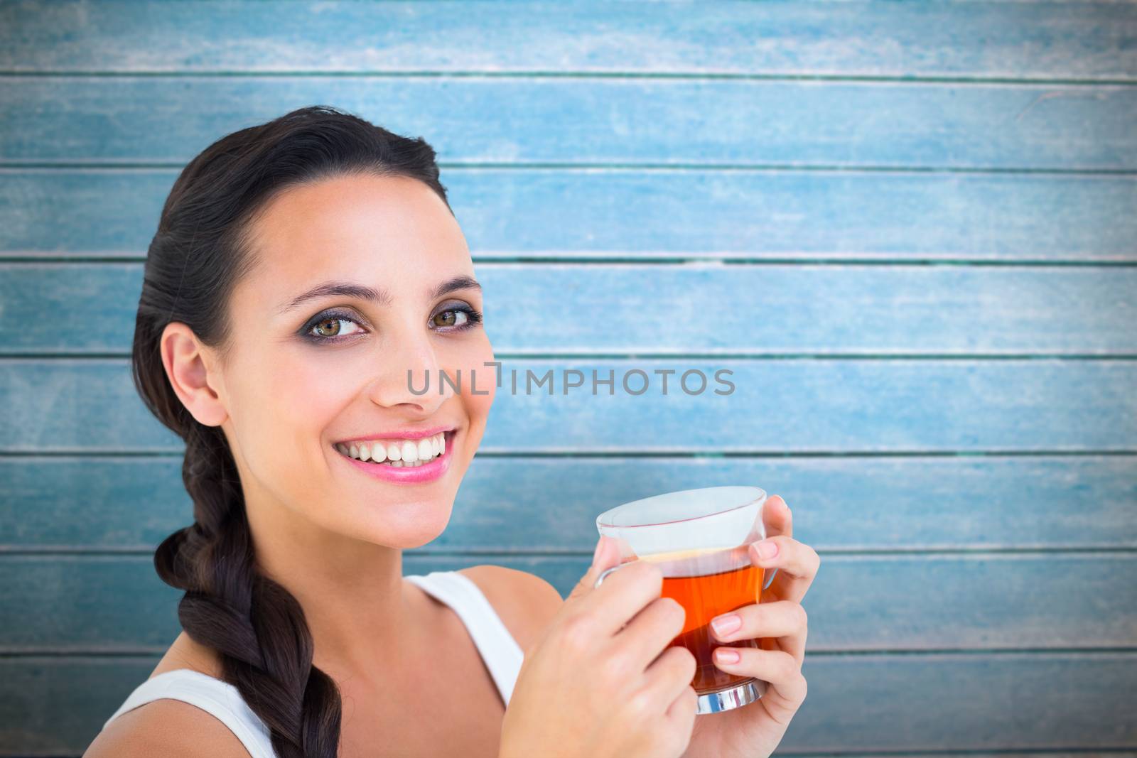 Pretty brunette having cup of tea against wooden planks