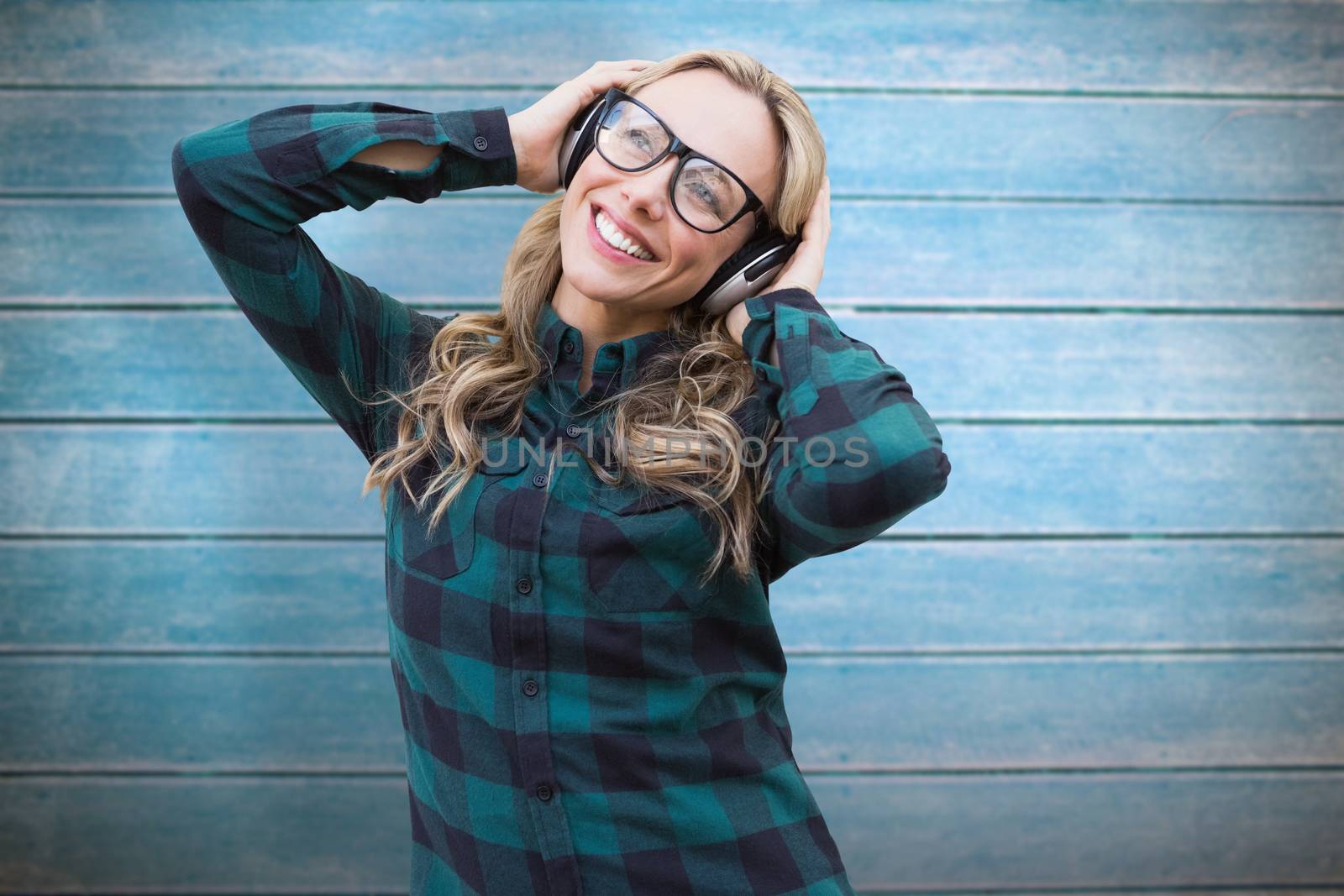 Pretty blonde listening to music against wooden planks