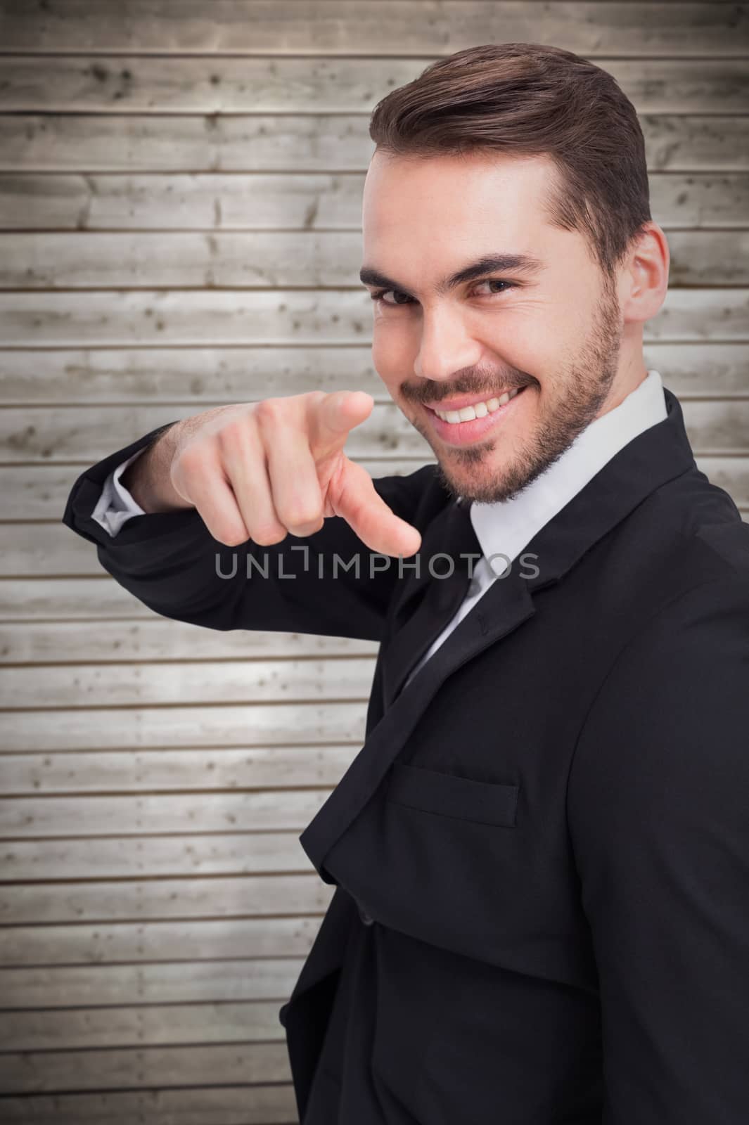 Happy businessman pointing his finger against wooden planks background