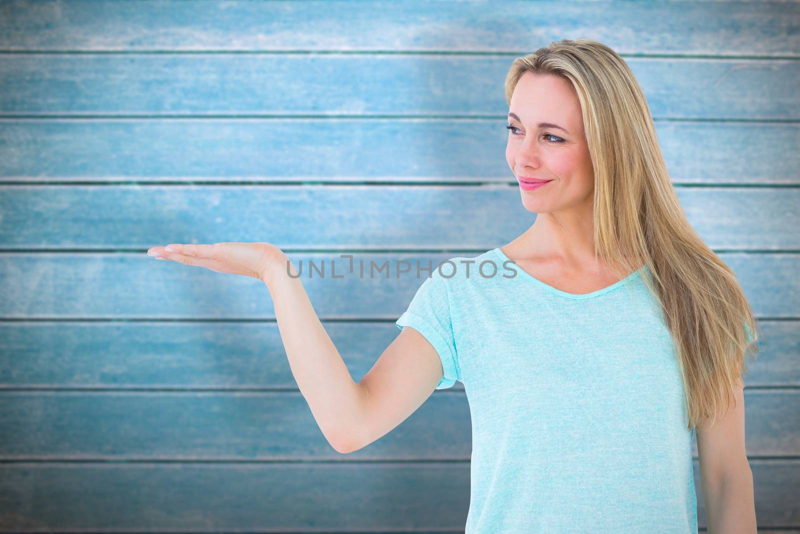 Composite image of pretty blonde smiling with hand out by Wavebreakmedia