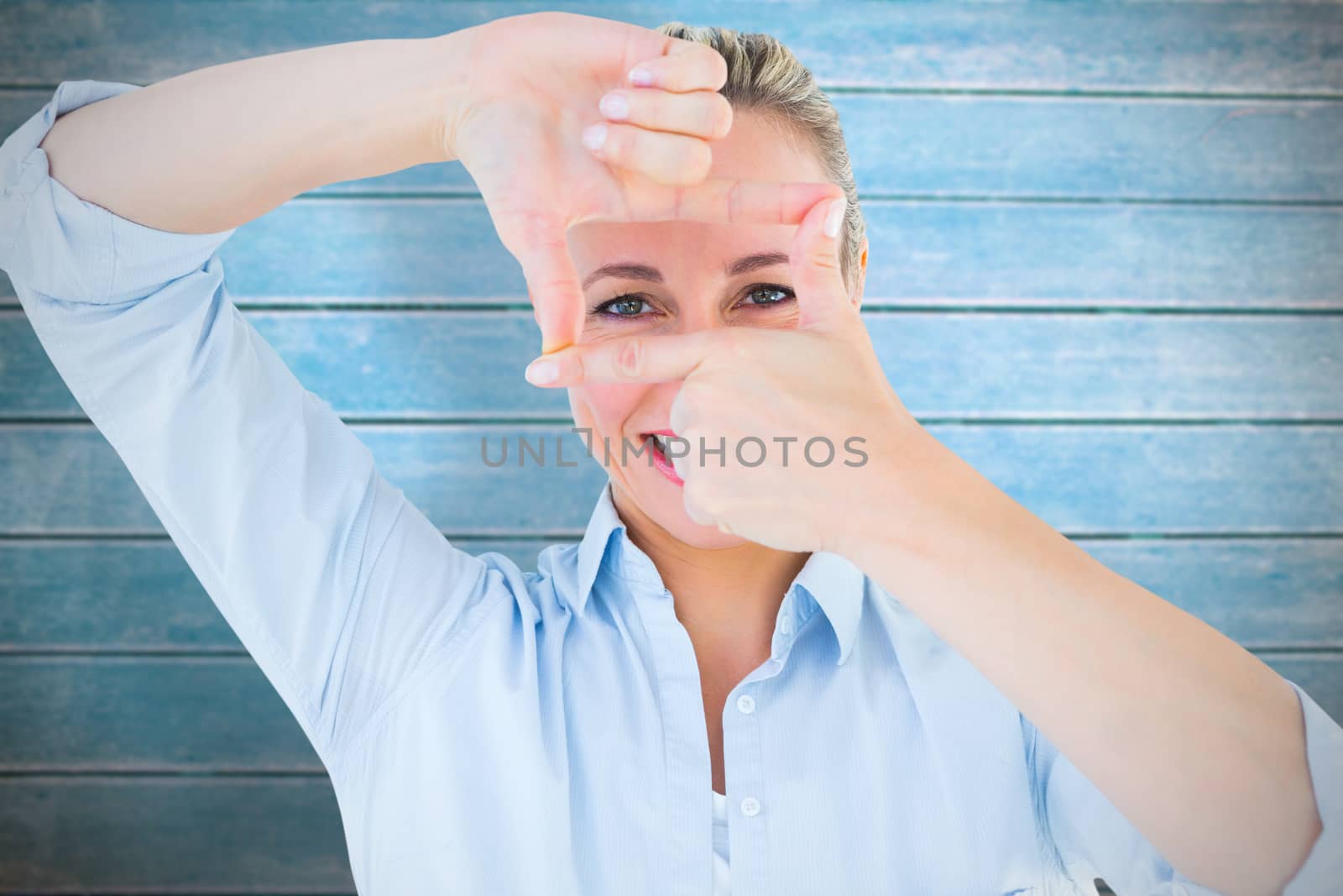 Smiling blonde making a hand gesture against wooden planks