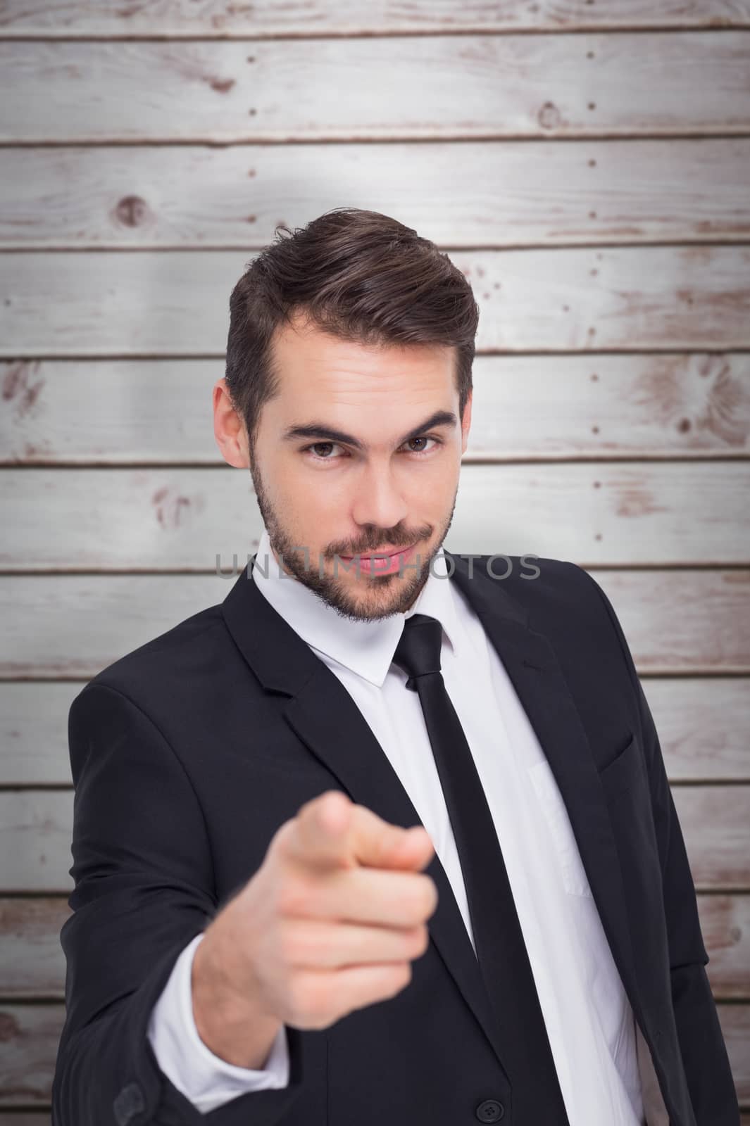 Smart businessman in suit pointing at camera against wooden planks