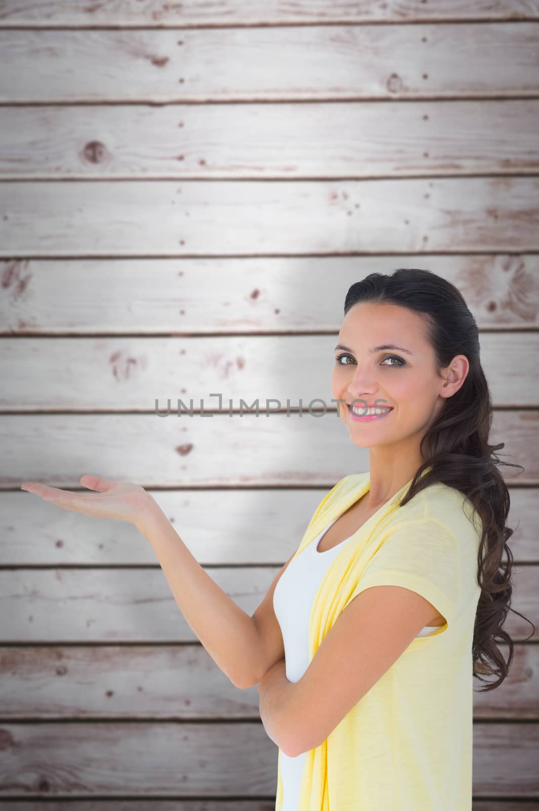 Pretty brunette smiling at camera against wooden planks