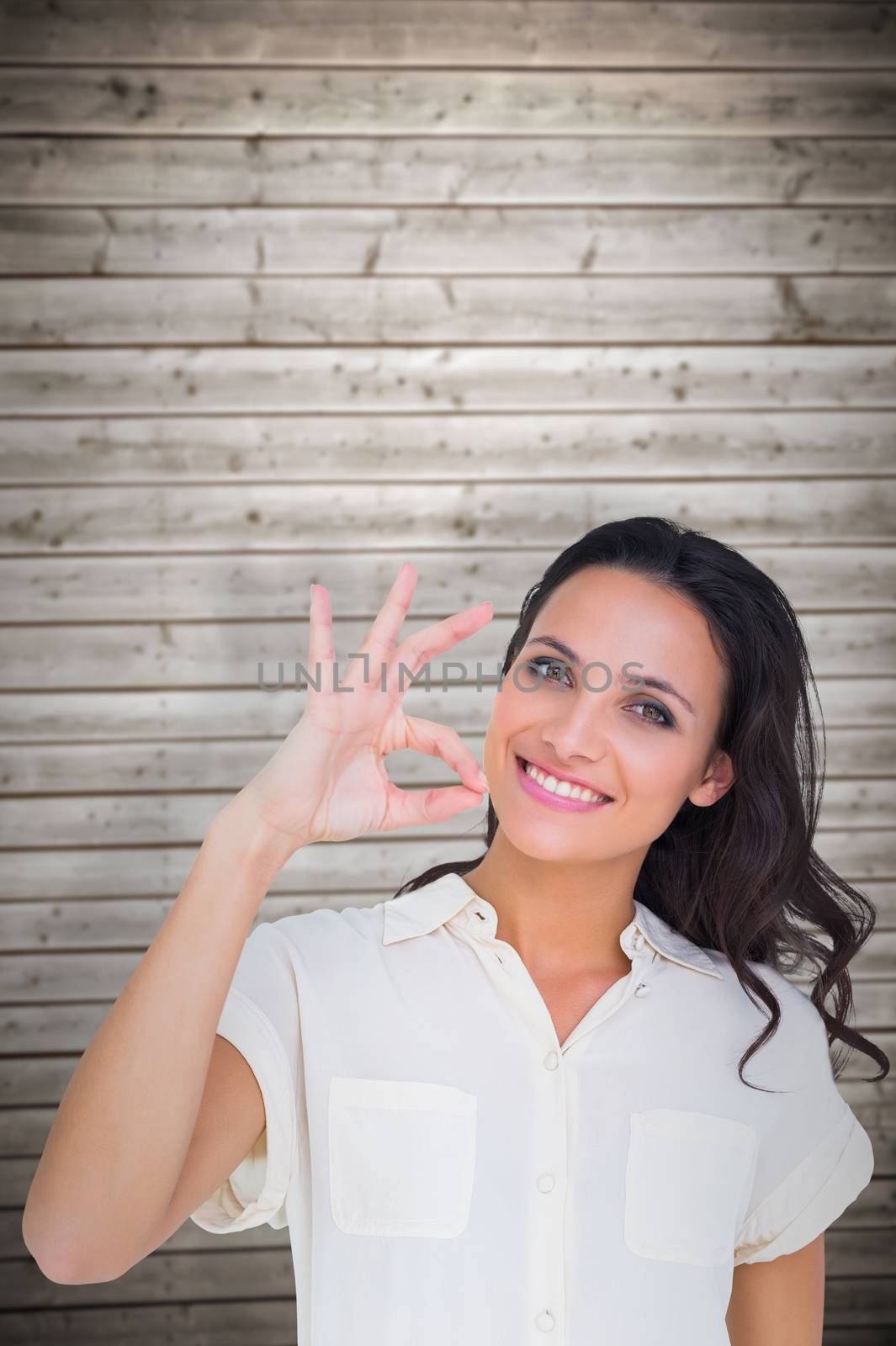 Pretty brunette making ok sign against wooden planks background