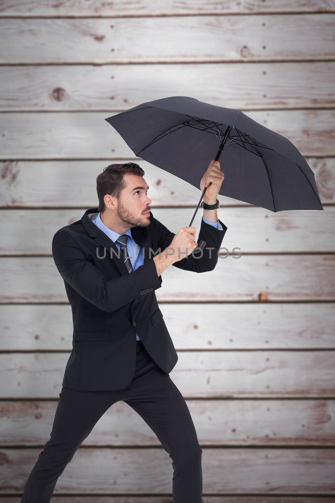 Composite image of businessman holding umbrella to protect himself by Wavebreakmedia